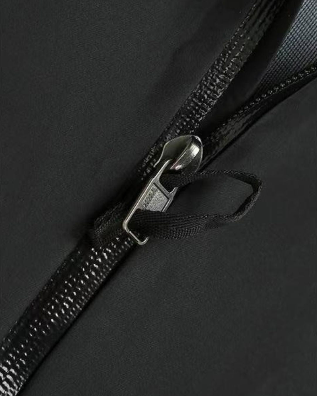 Close-up of a black waterproof hiking jacket featuring a durable, taped-seam water-resistant zipper pull.