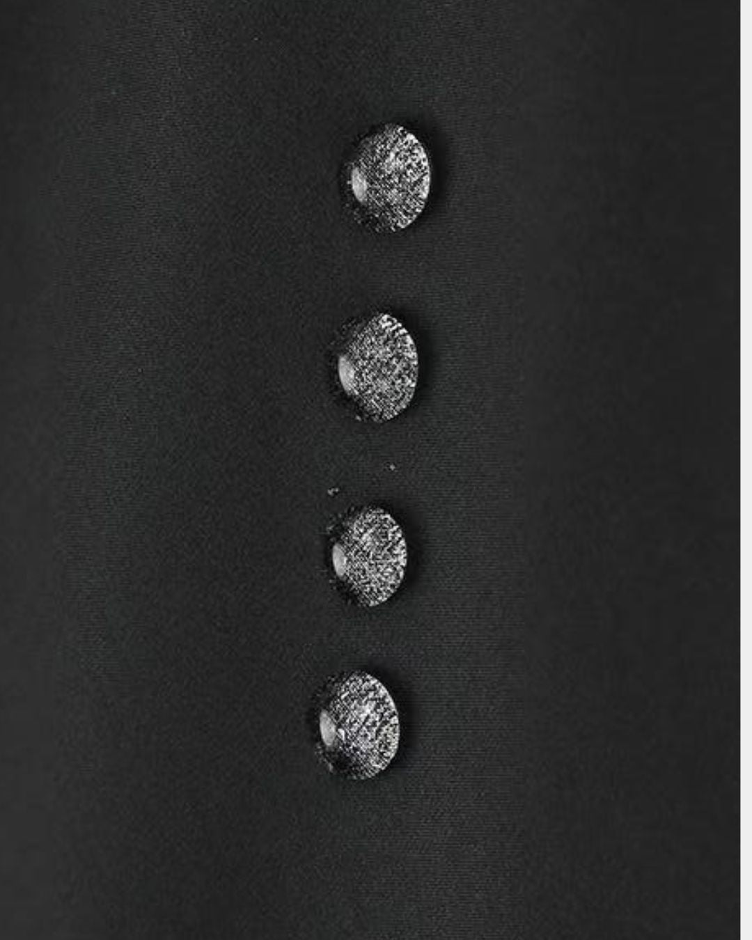 Water droplets beading on the black waterproof fabric of a technical hiking windbreaker jacket.