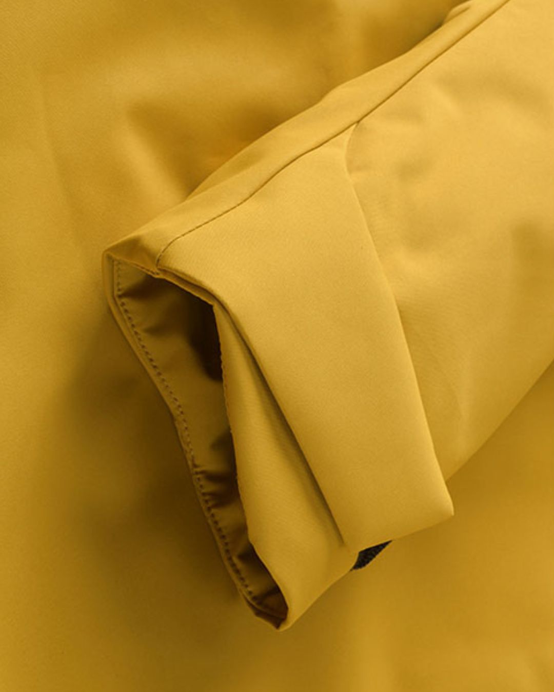 Close-up of yellow windbreaker jacket cuff showing clean stitching and smooth fabric finish