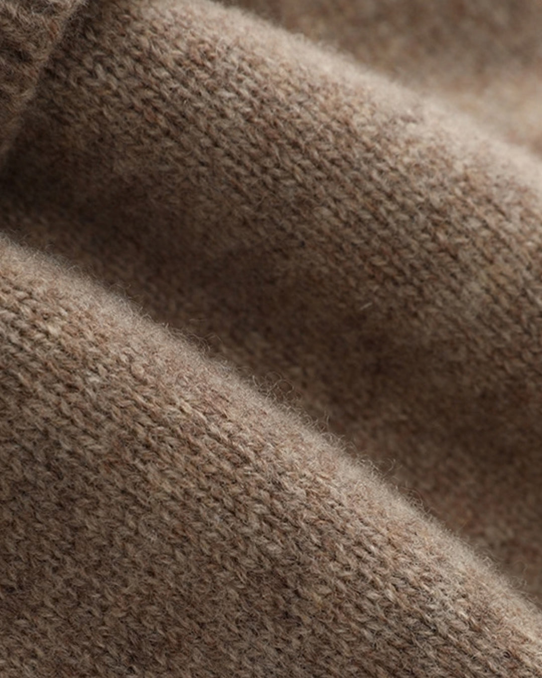 Close-up of a soft, tan wool knit fabric featuring a textured ribbed design from a men's cuffed beanie.