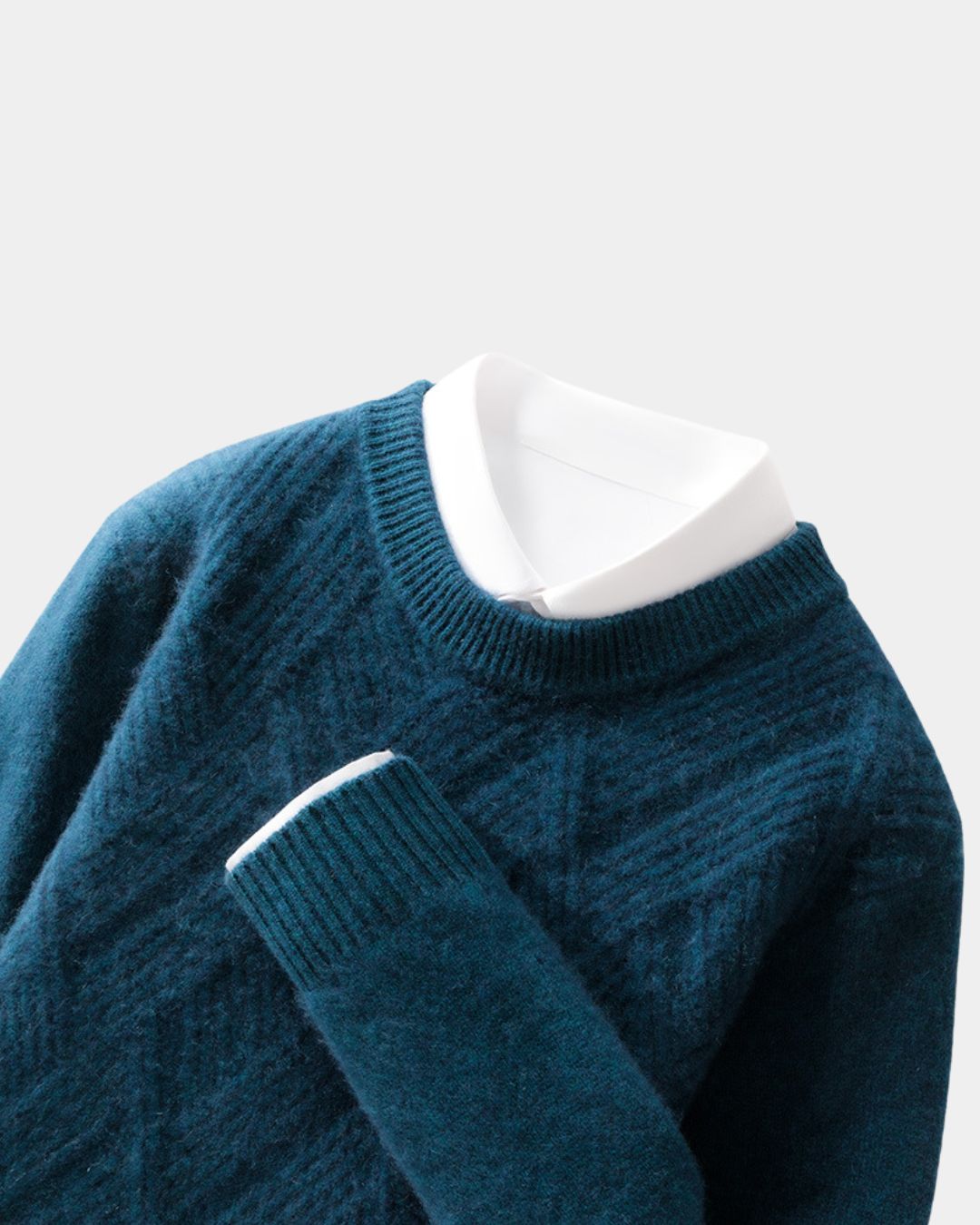 Teal blue wool crewneck sweater with a raised diamond knit pattern, ribbed trim, and a white collared shirt layered underneath.