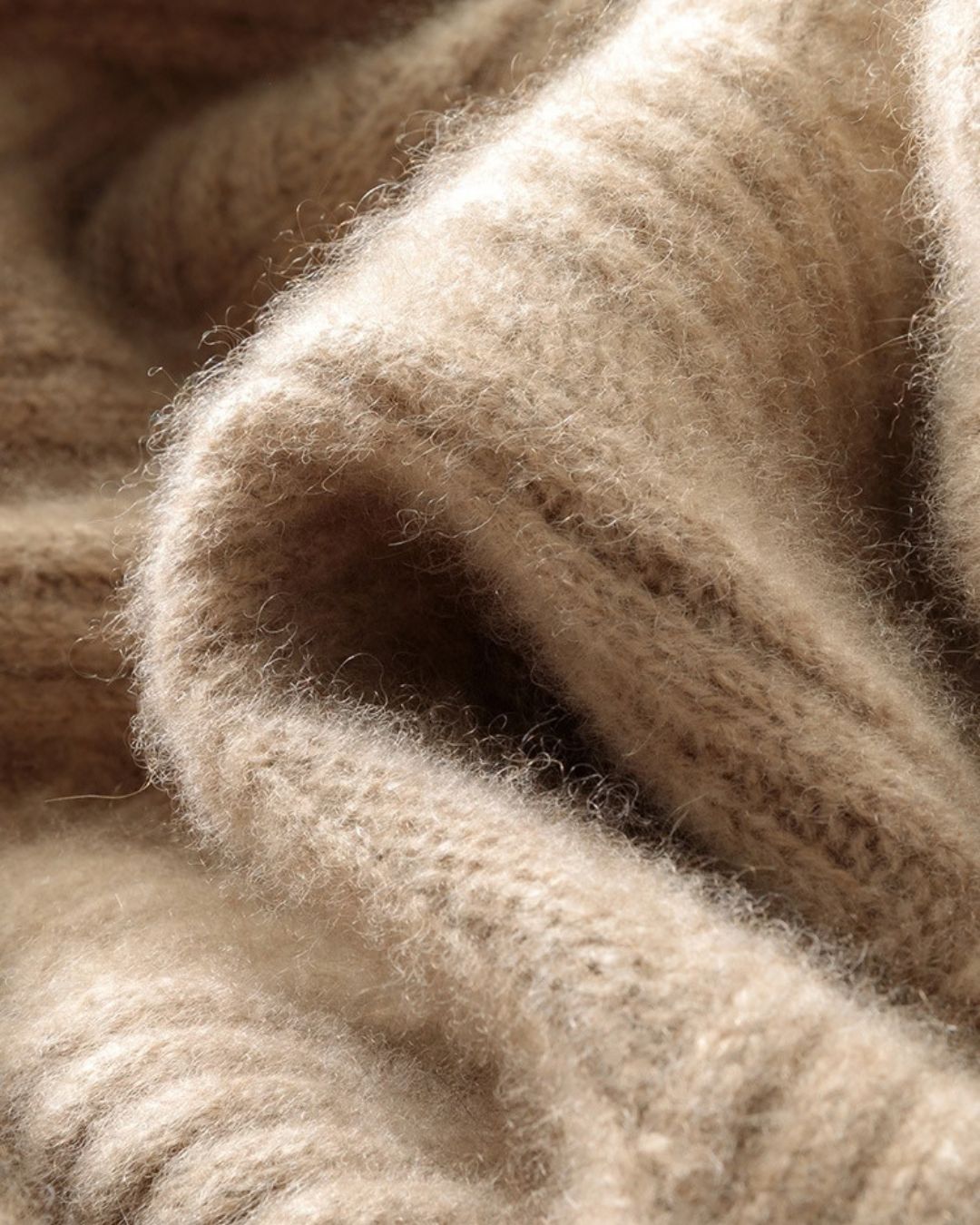 Close-up of a beige wool knit sweater featuring a soft, textured diamond pattern and thick, warm fabric.