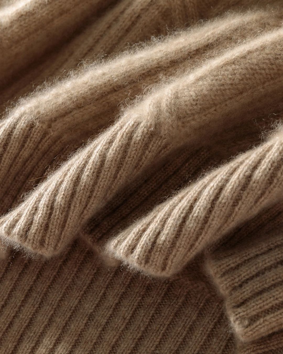 Close-up of a beige men’s wool crewneck sweater featuring a thick, textured knit and ribbed detailing.