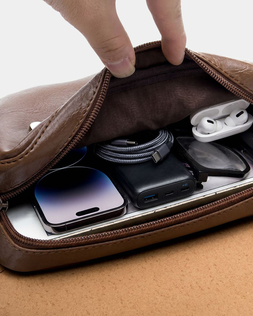 Interior view of Torino men's brown crossbody bag showing main compartment with phone, power bank and ear buds.