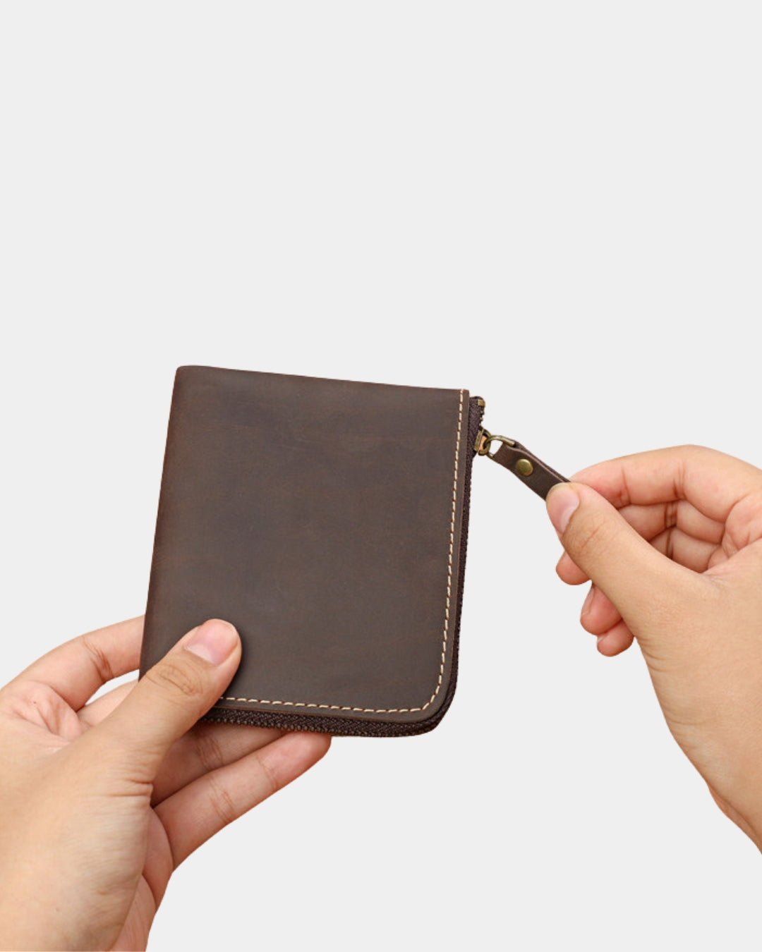 Hands holding a brown genuine cowhide leather wallet with a secure full zip-around closure and contrast stitching.