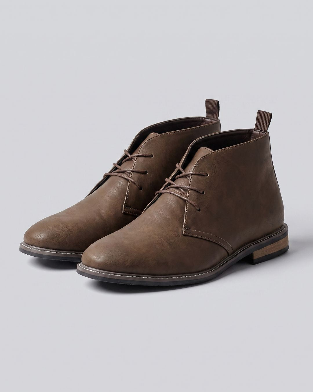 A pair of men's brown leather lace-up ankle chukka boots with a low stacked heel and pull tabs, by Hudson & Tate.