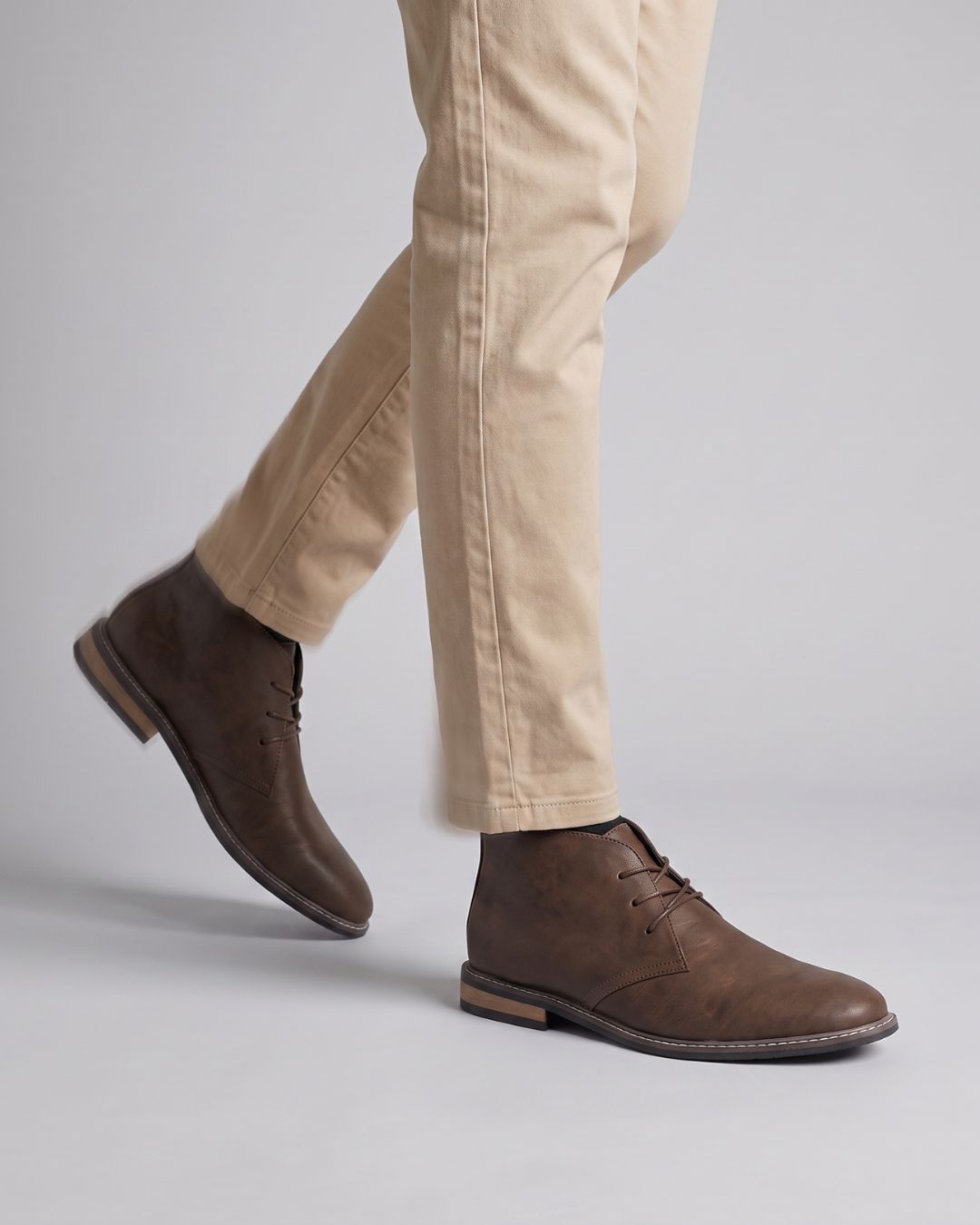 A person wearing dark brown suede chukka boots by Hudson & Tate.