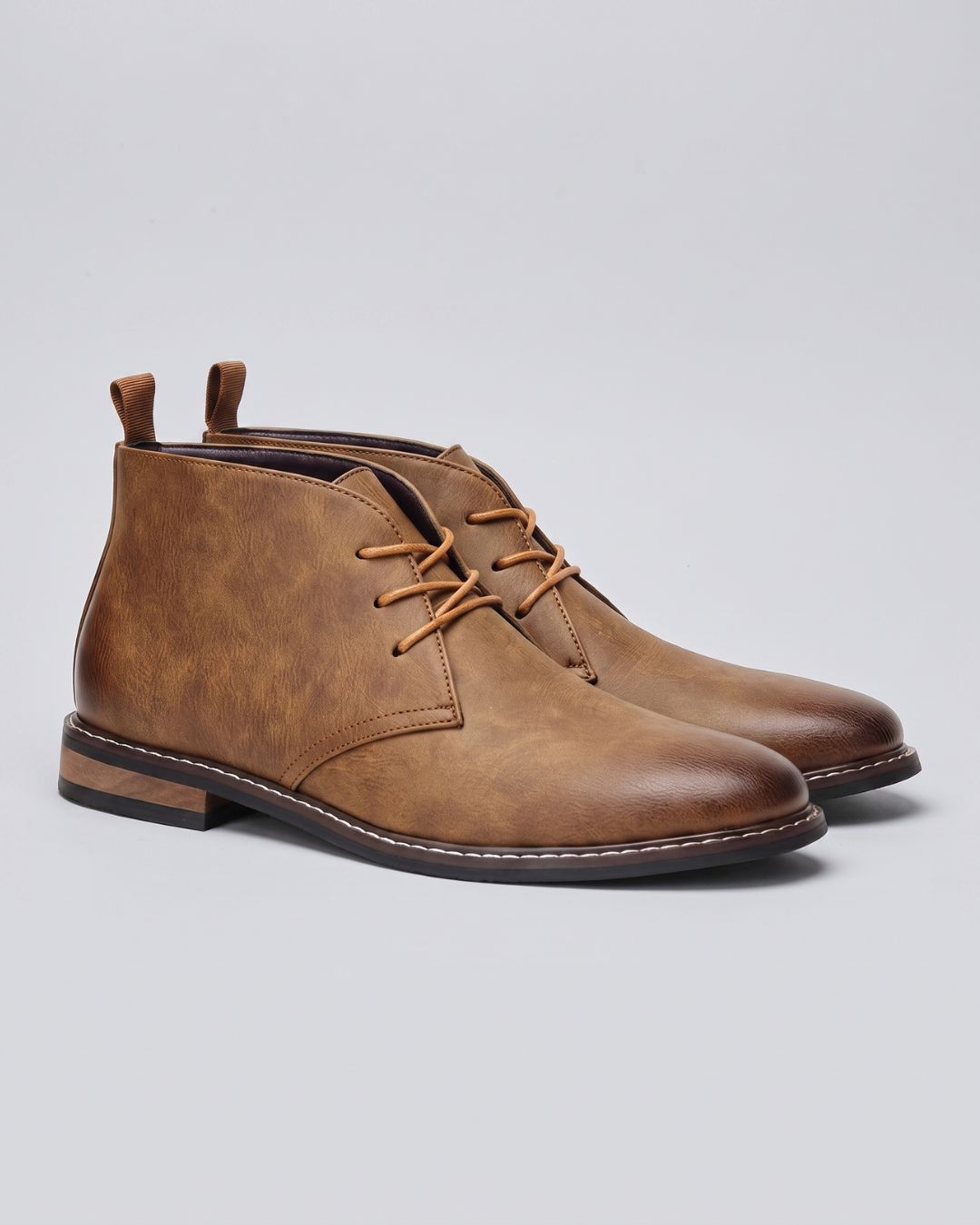 A pair of men's chukka-style ankle boots in distressed tan leather, featuring tan laces and low stacked heels, by Hudson & Tate.