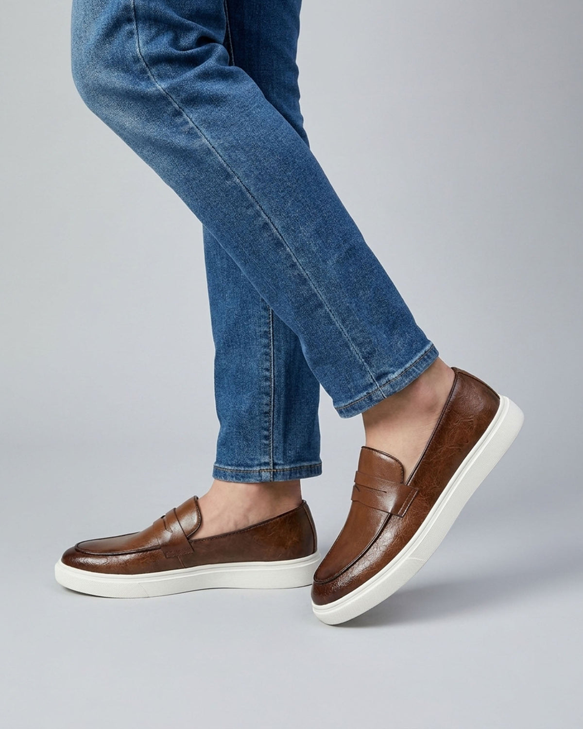 Belmont men's brown penny loafer sneakers mid-stride styled with blue denim jeans
