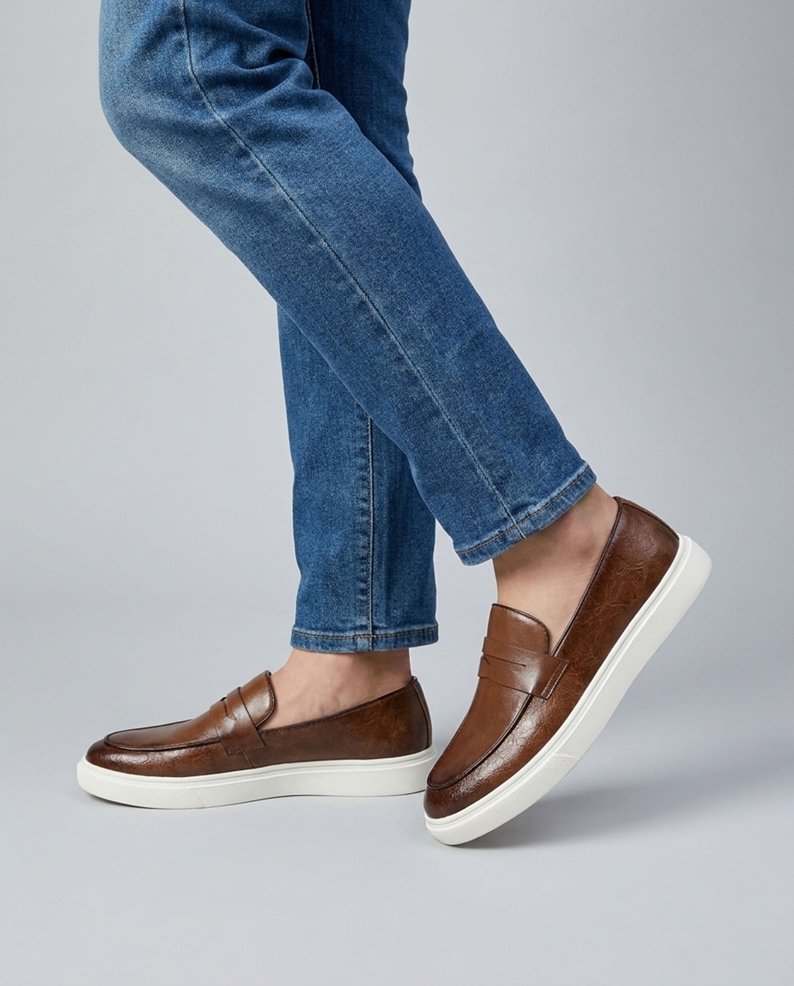Belmont men's brown penny loafer sneakers mid-stride styled with blue denim jeans