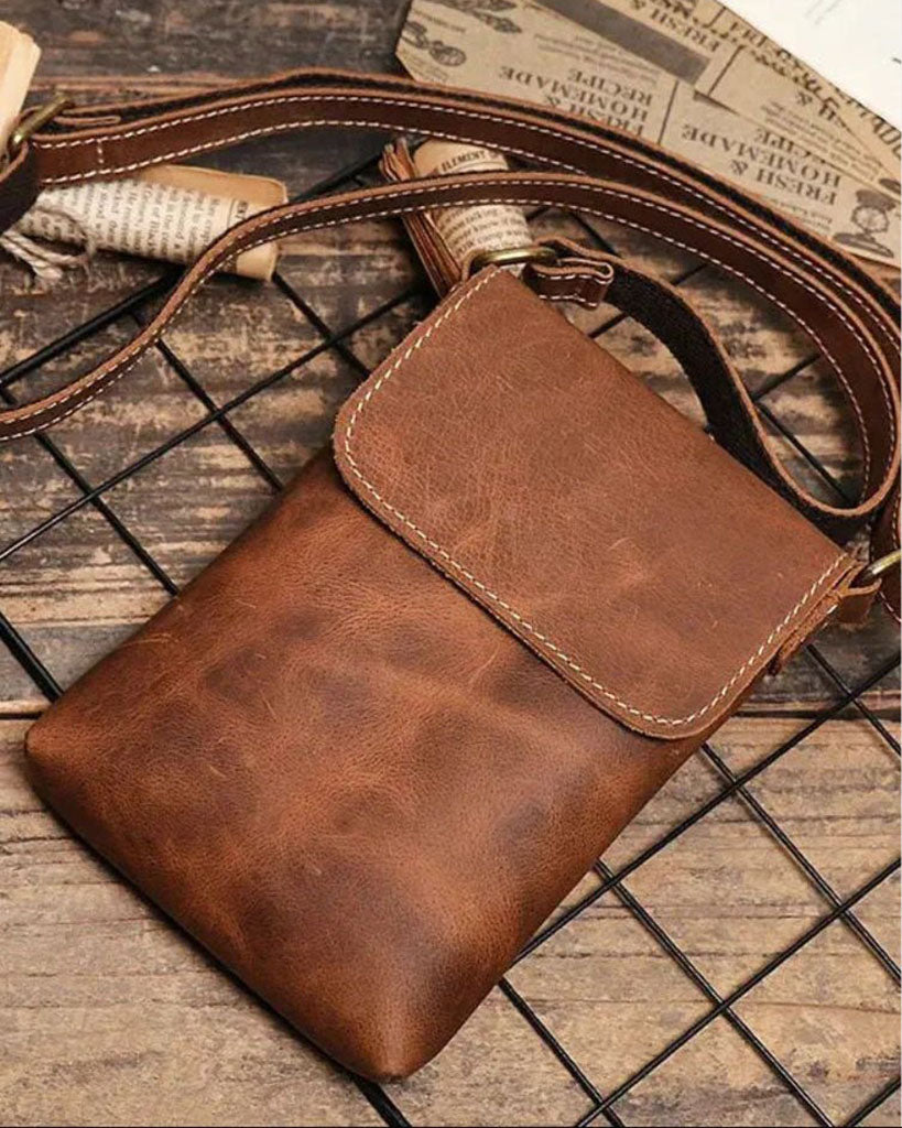 Brescia men's brown genuine leather phone bag with contrast stitching and antique brass hardware styled on rustic surface
