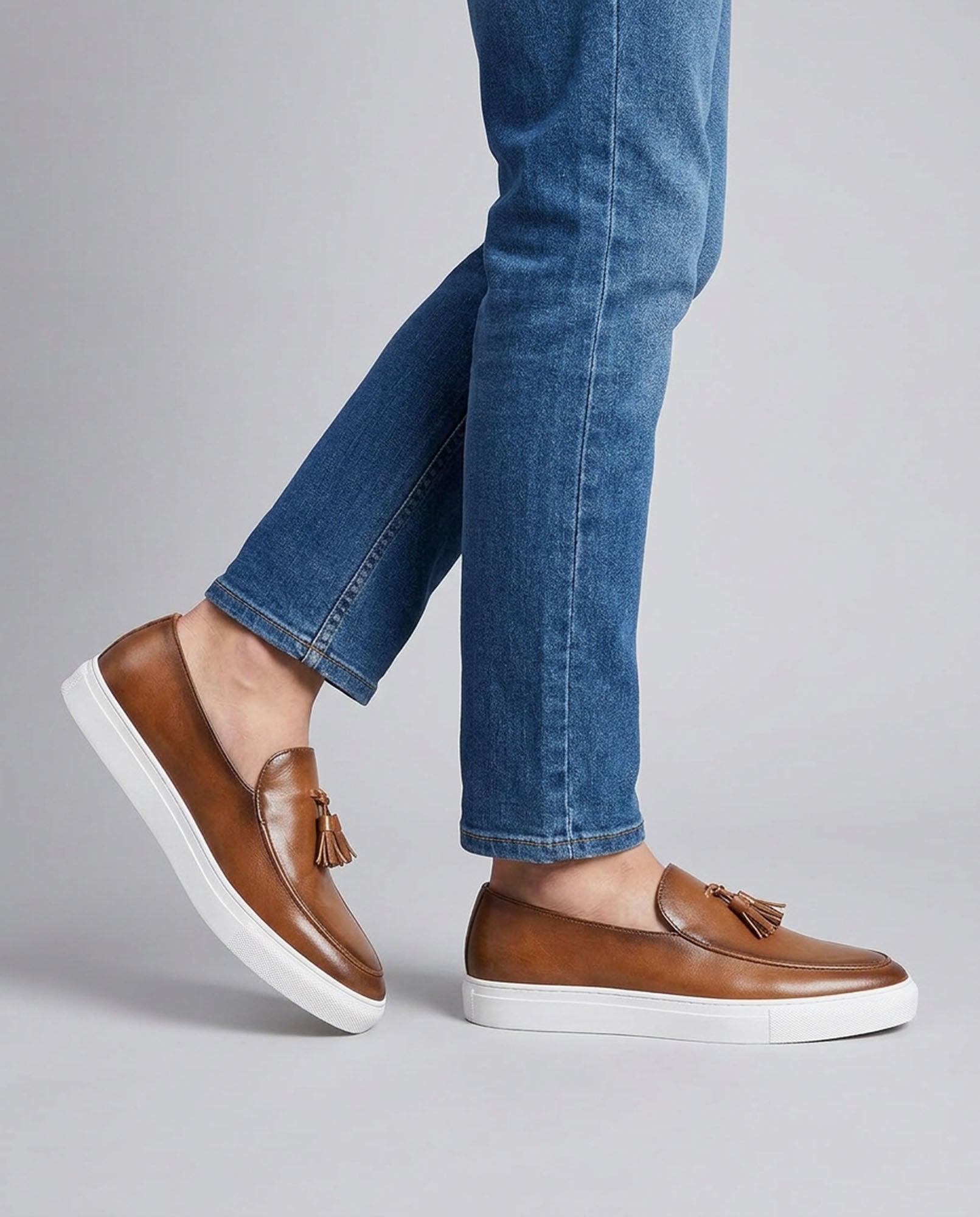 Capri men's cognac leather tassel loafers mid-stride styled with blue denim jeans