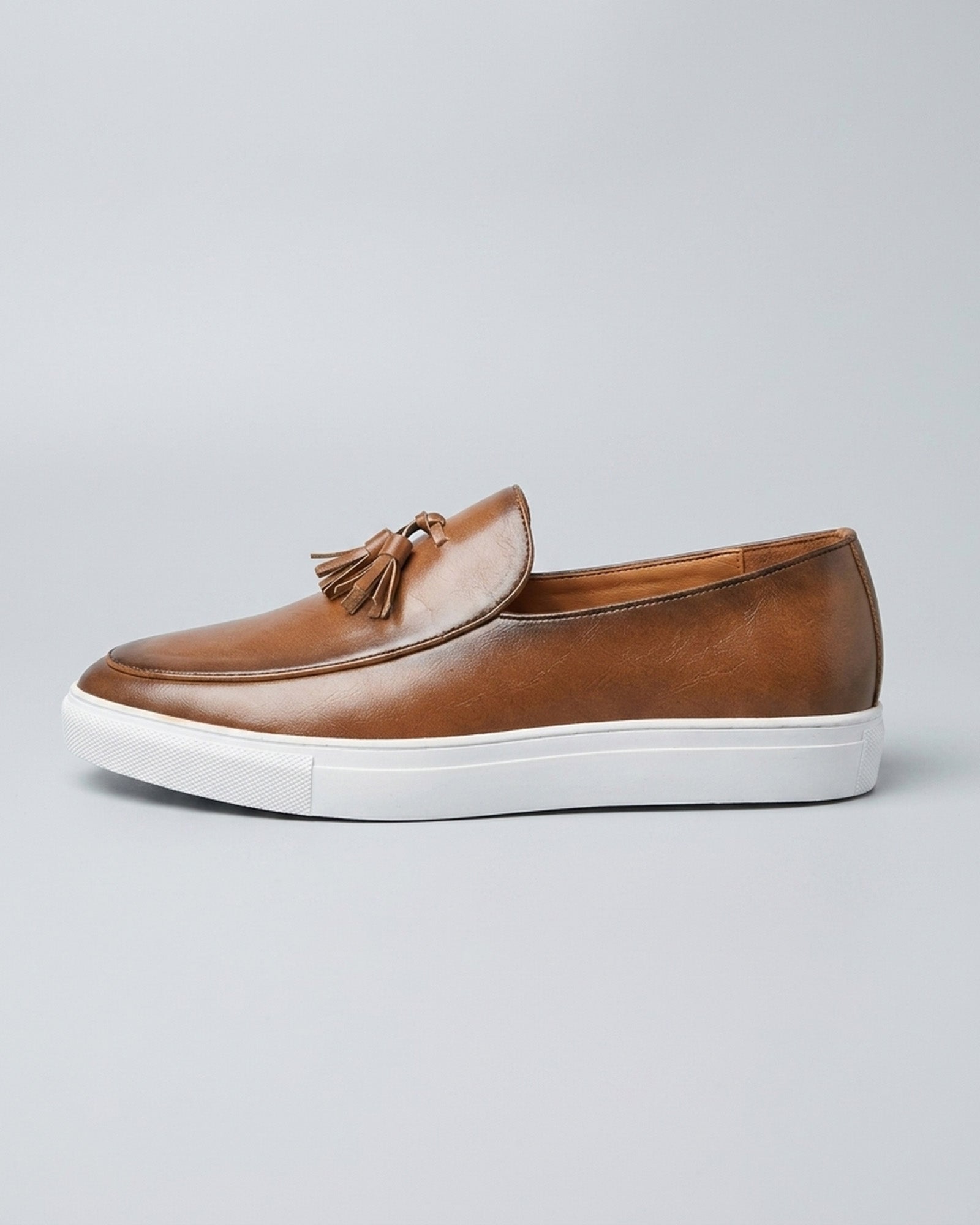 Side view of Capri men's cognac leather tassel loafer with white cupsole