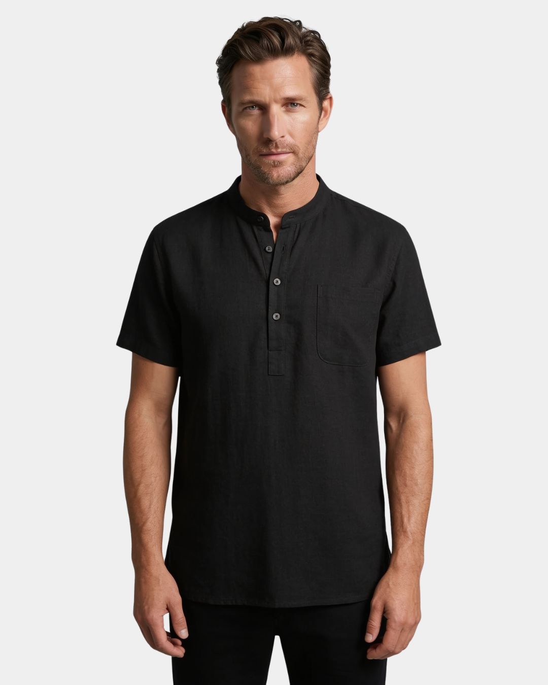A man wearing a black short-sleeve henley shirt with a buttoned collar and a chest pocket, photographed against a light gray studio background.