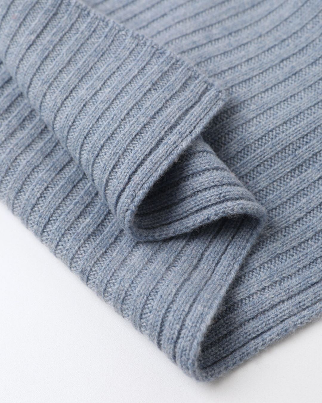 Soft blue cashmere scarf featuring a textured ribbed knit design for a warm, minimalist winter look.