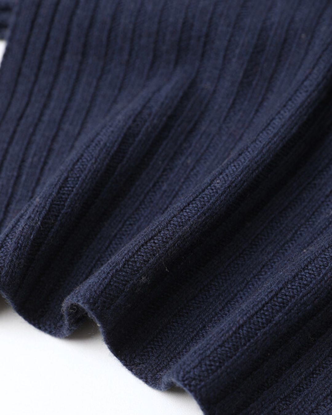 Close-up of navy blue cashmere knit fabric with a soft, vertical ribbed texture for a winter scarf or hat.