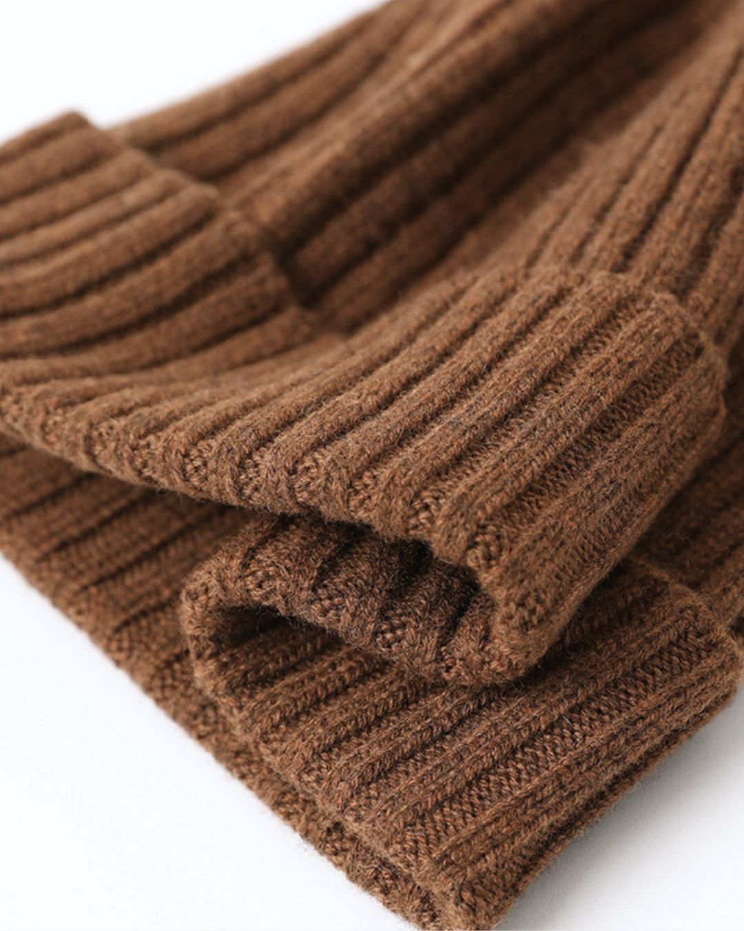Close-up of a brown cashmere winter beanie featuring a soft, ribbed knit texture and a folded cuff design.