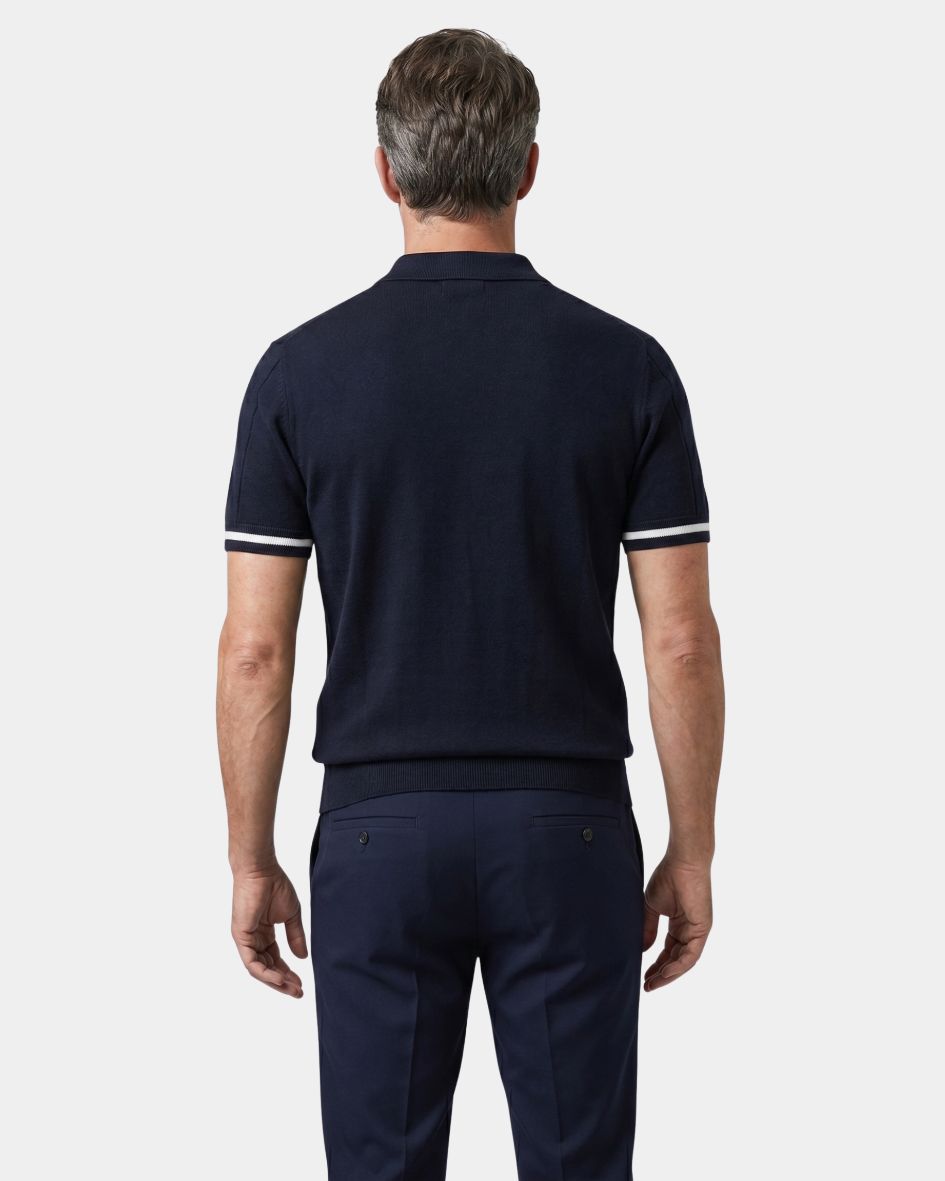 Man wearing a navy polo shirt and pants on a white background