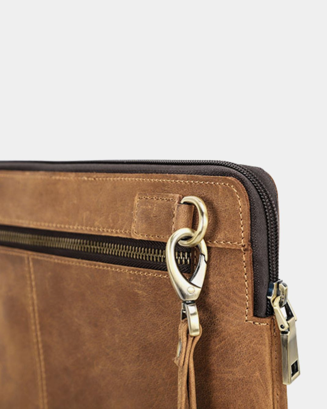 Close-up of a brown leather laptop sleeve with a top zipper, black trim, and a gold-tone metal ring and zipper pull.