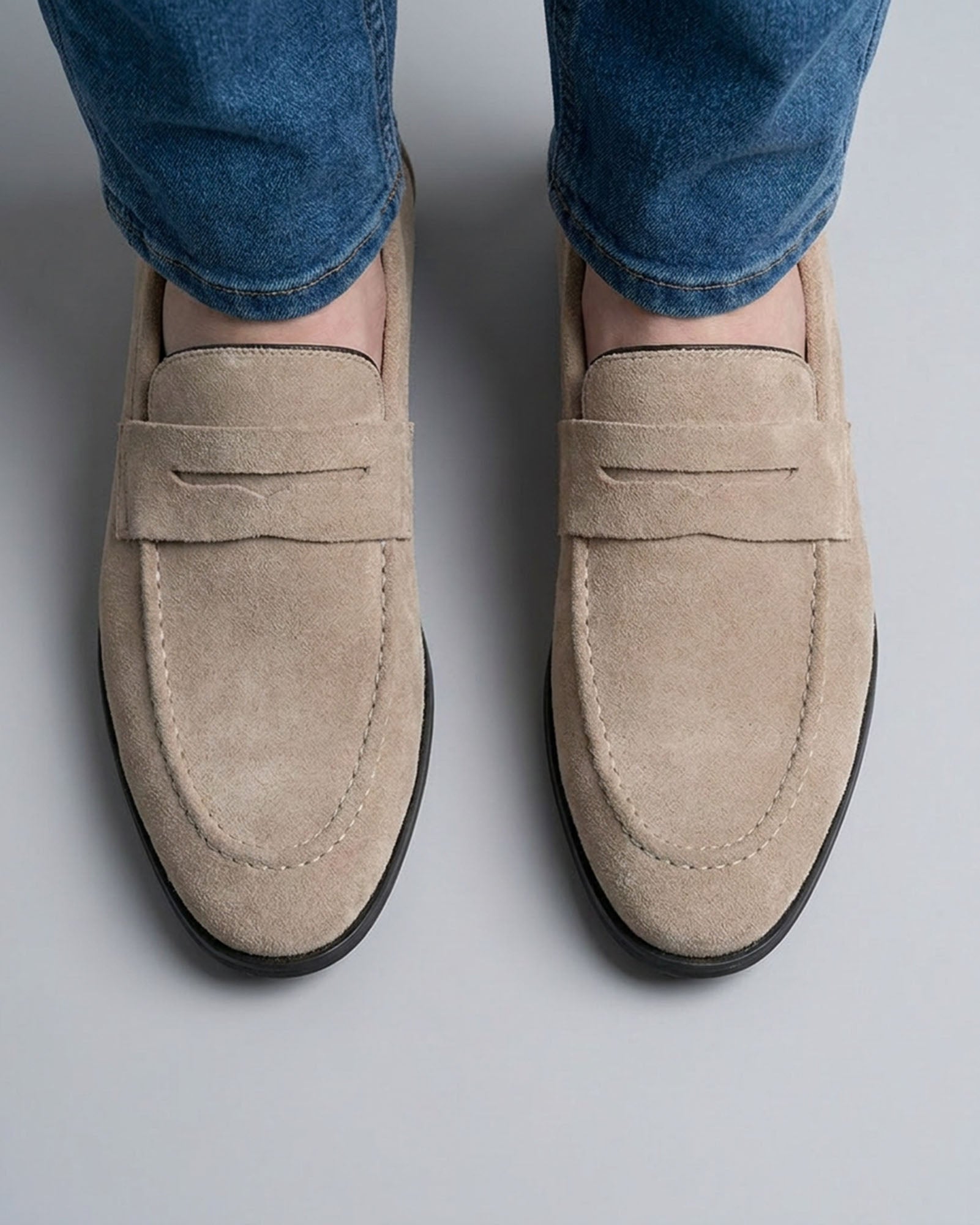 Overhead view of Harper men's beige suede penny loafers with penny strap detail styled with blue denim jeans