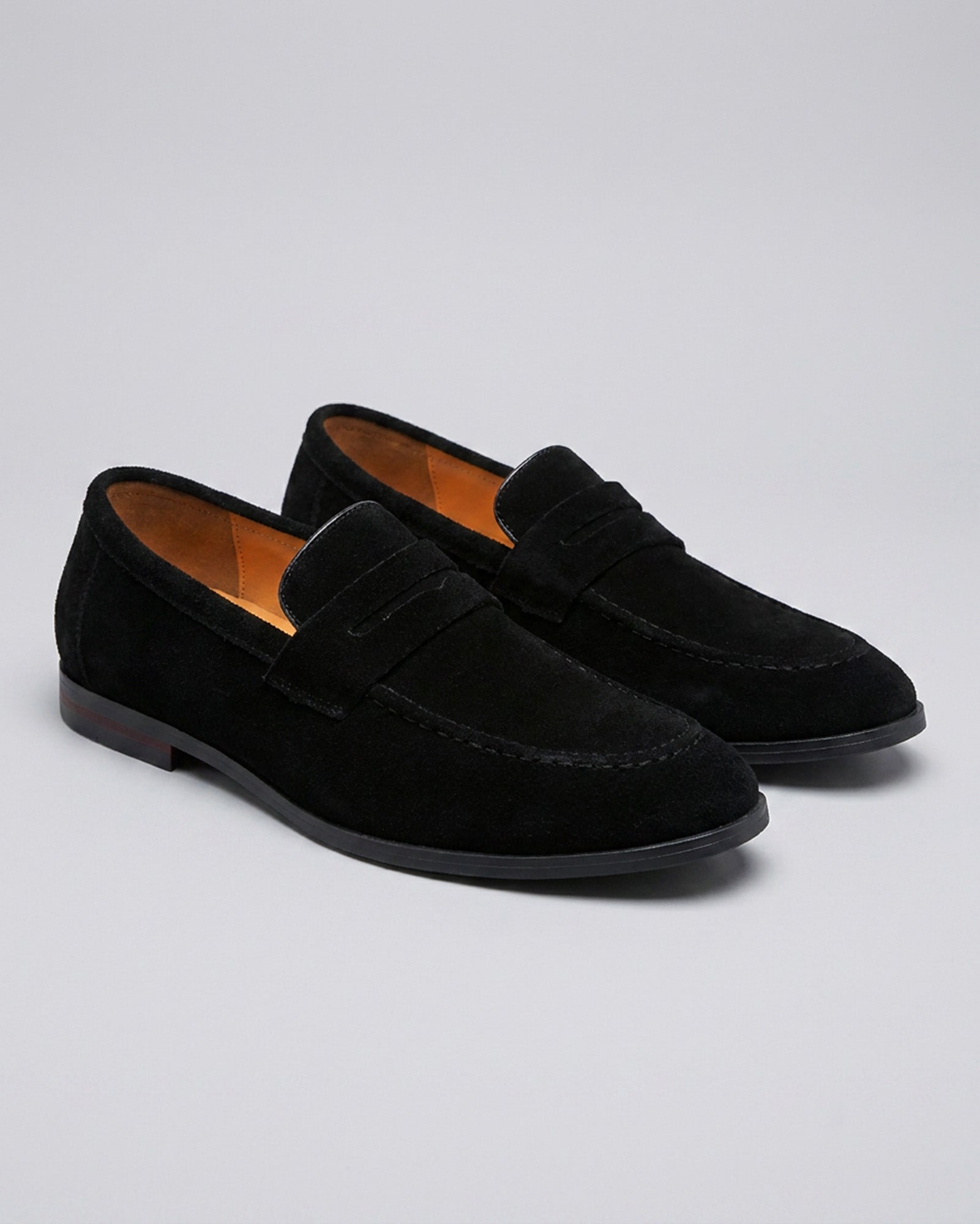 Pair of Harper men's black suede penny loafers on grey background
