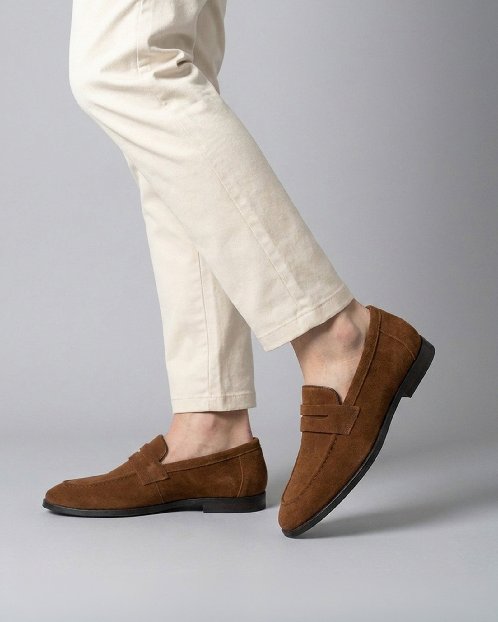 Harper men's cognac suede penny loafers mid-stride styled with cream chino trousers