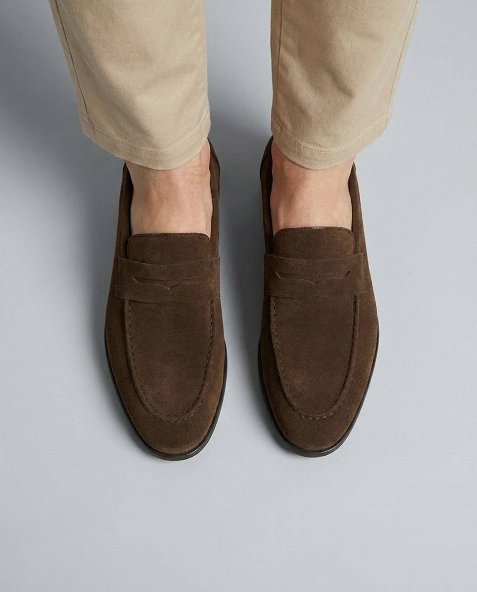 Overhead view of Harper men's dark brown suede penny loafers with penny strap detail styled with beige chino trousers