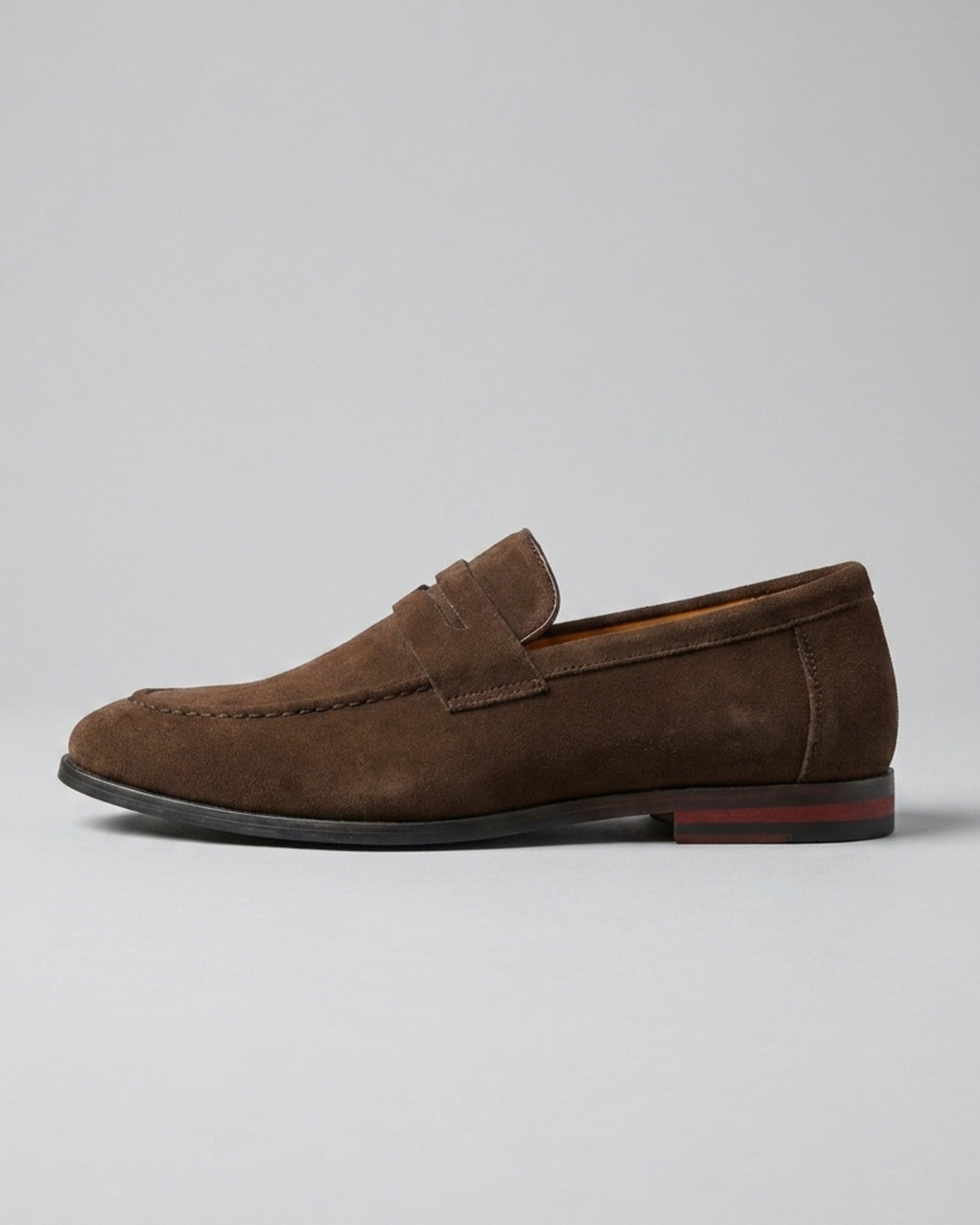 Side view of Harper men's dark brown suede penny loafer with red sole detail