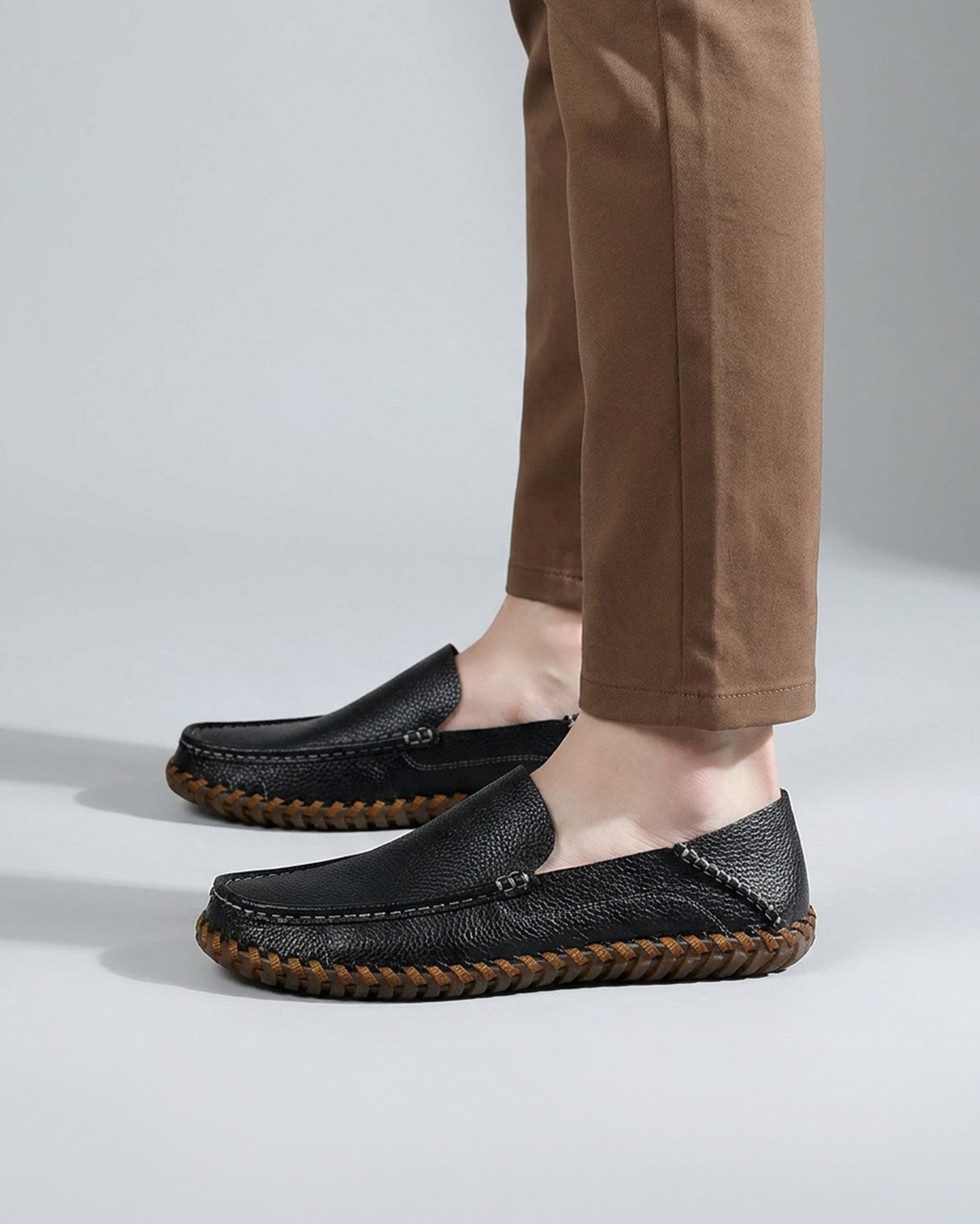 Side profile of Marlow men's black leather driving loafers styled with tan chinos