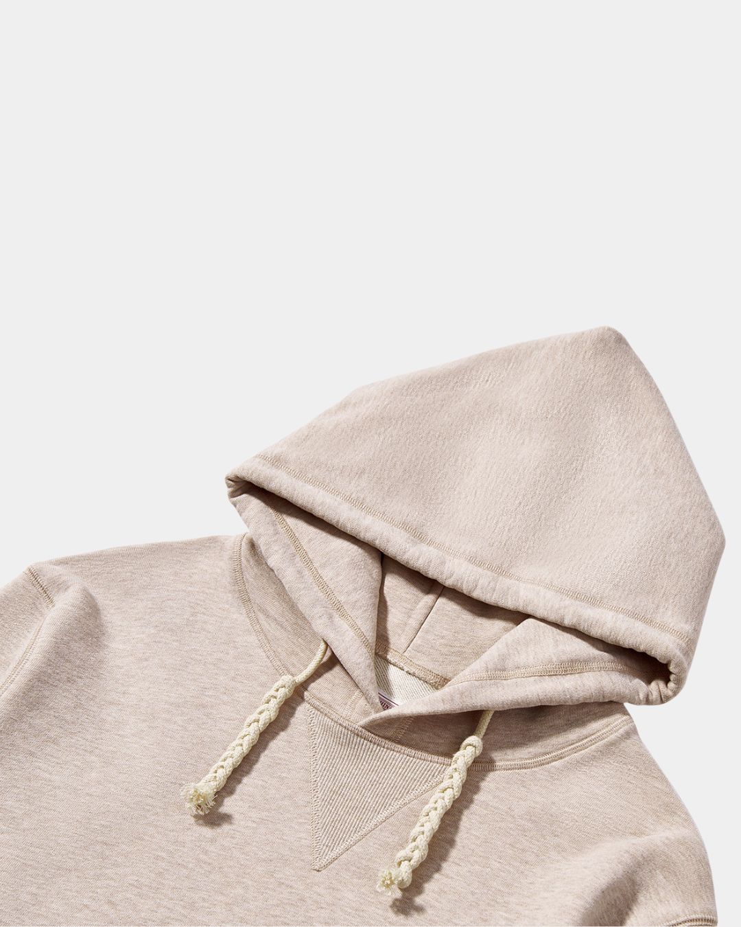 Beige oversized cotton pullover hoodie with a drawstring hood and textured fabric detail.
