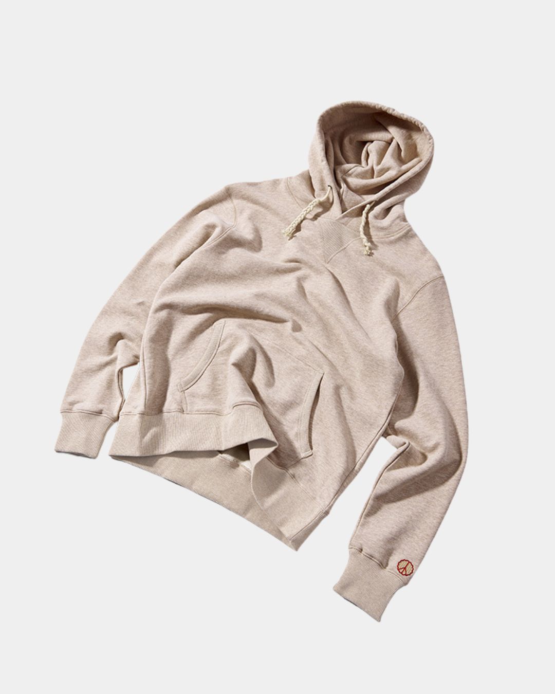 Beige oversized cotton pullover hoodie with drawstring hood, kangaroo pocket, and small embroidered peace symbol on sleeve.