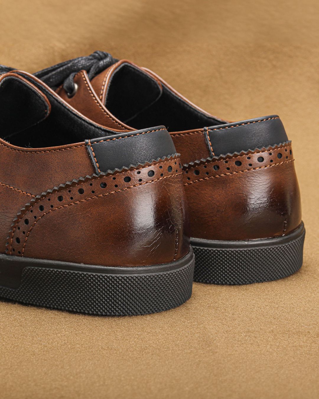 Brown faux leather dress sneakers with black heel tabs, brogue detailing, and textured black rubber soles.