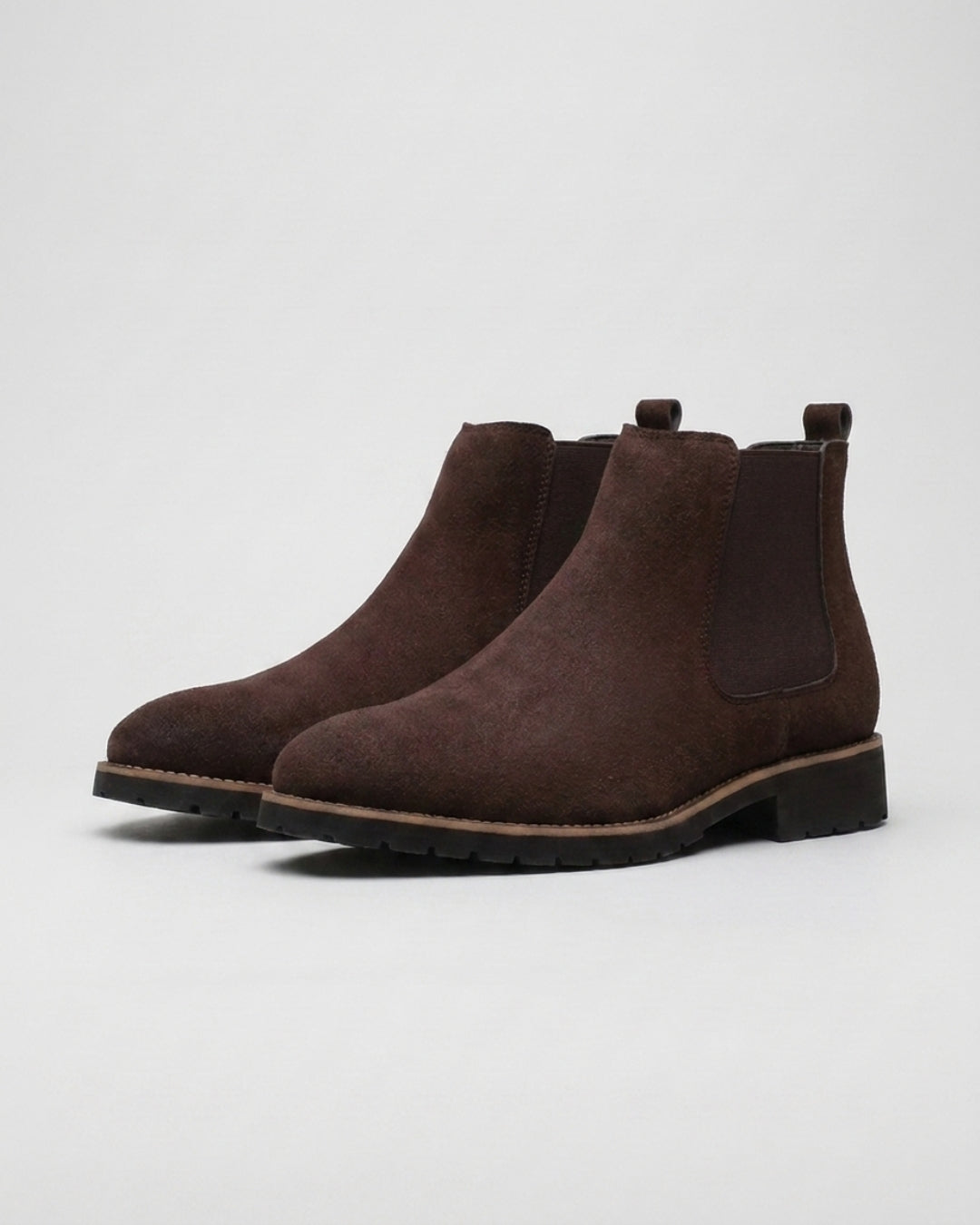 Men’s brown suede Chelsea boots with elastic side panels, rounded toes, and durable rubber outsoles on a light background.