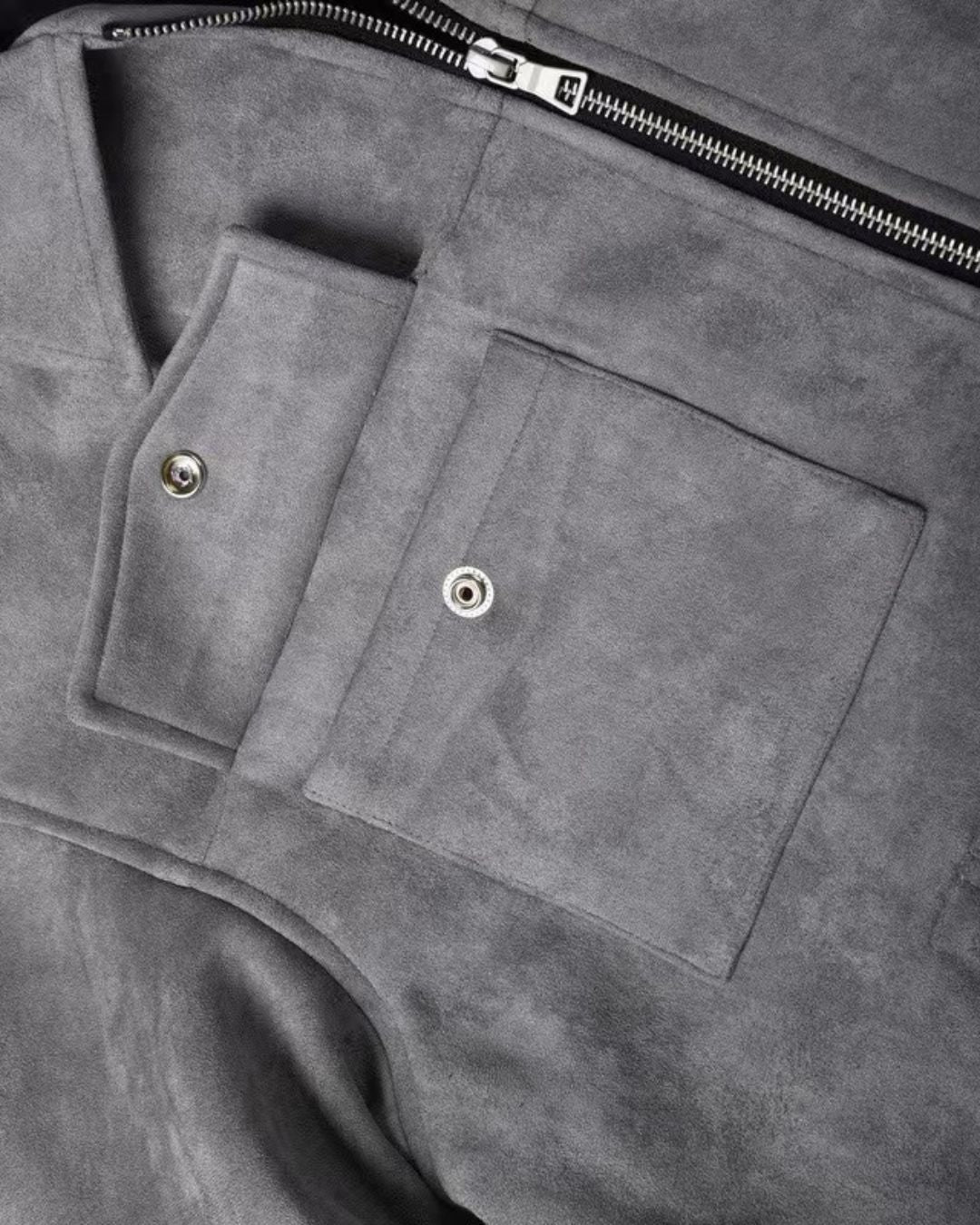 Close-up of a gmen's gray suede look casual zip-up overshirt jacket with a front zipper, flap pocket, and snap-button detail.