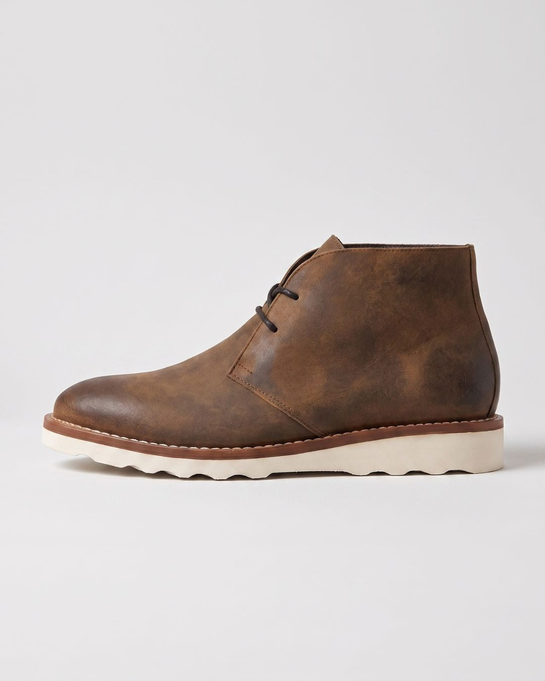 Men’s brown faux leather chukka boots with a rounded toe, lace-up ankle design, and a thick, white chunky foam sole.