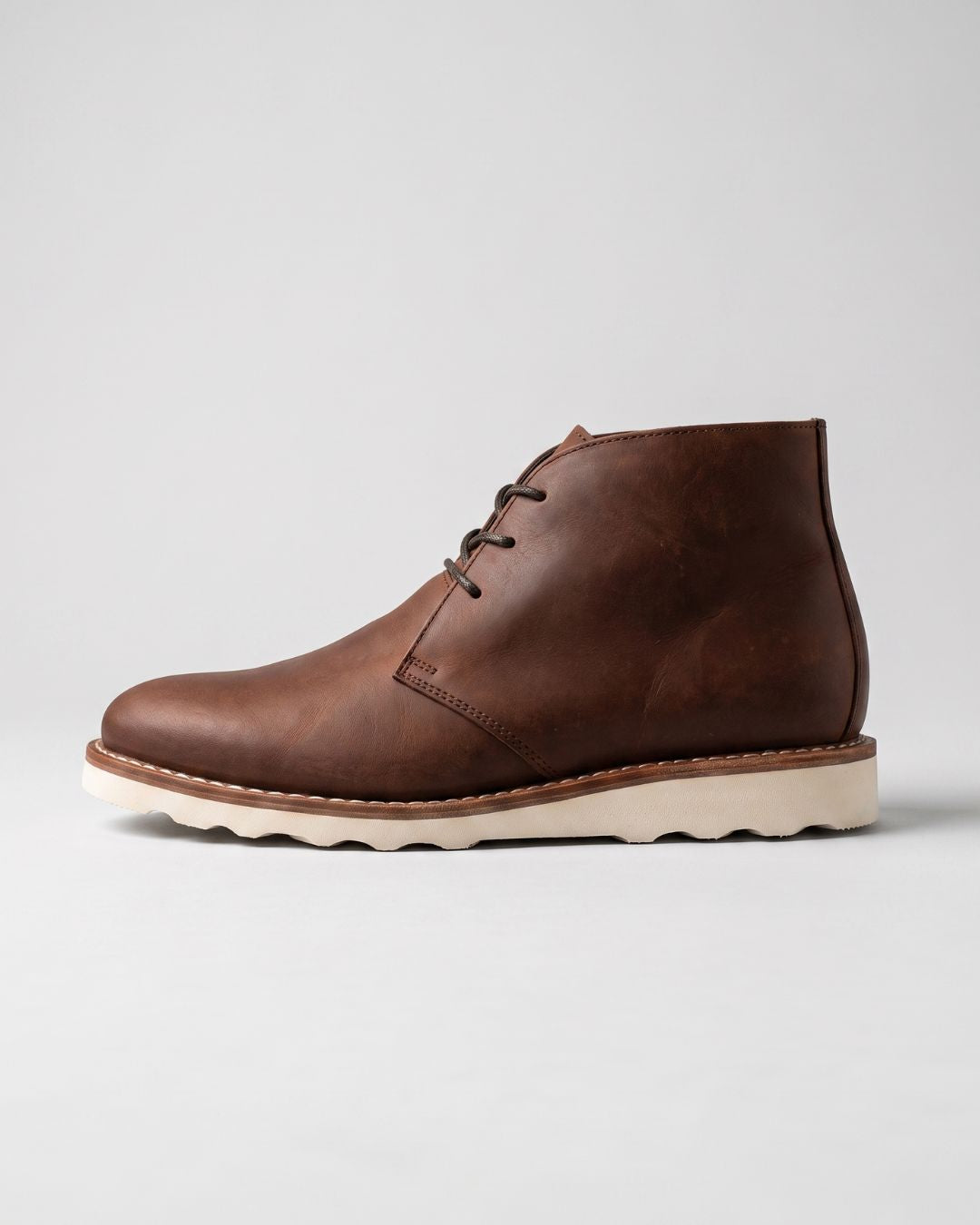 Men’s brown faux leather chukka boots with a lace-up ankle design and a chunky white sneaker-inspired foam sole.