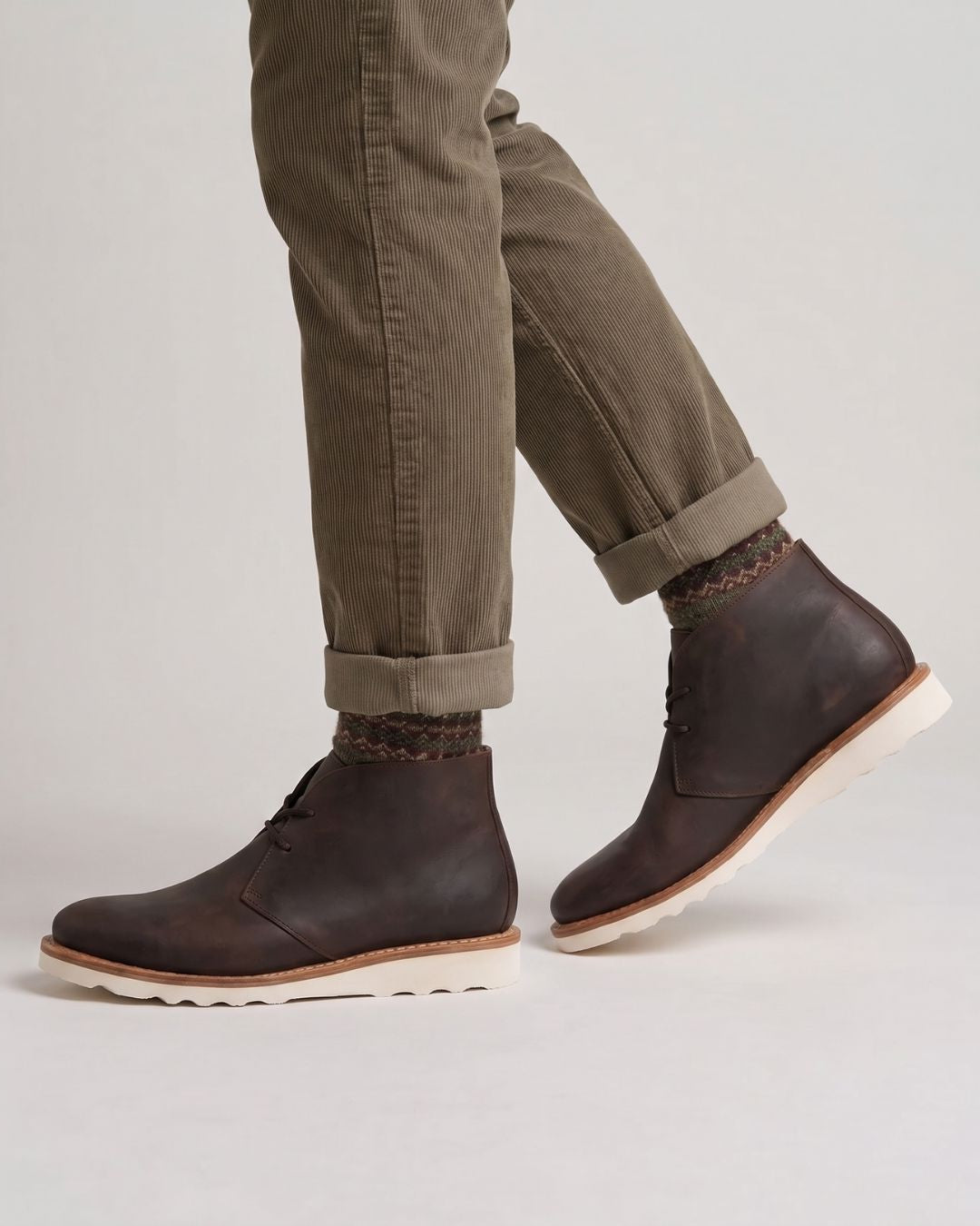 Men’s brown faux leather chukka boots featuring a chunky white sneaker-inspired foam sole and lace-up ankle design.