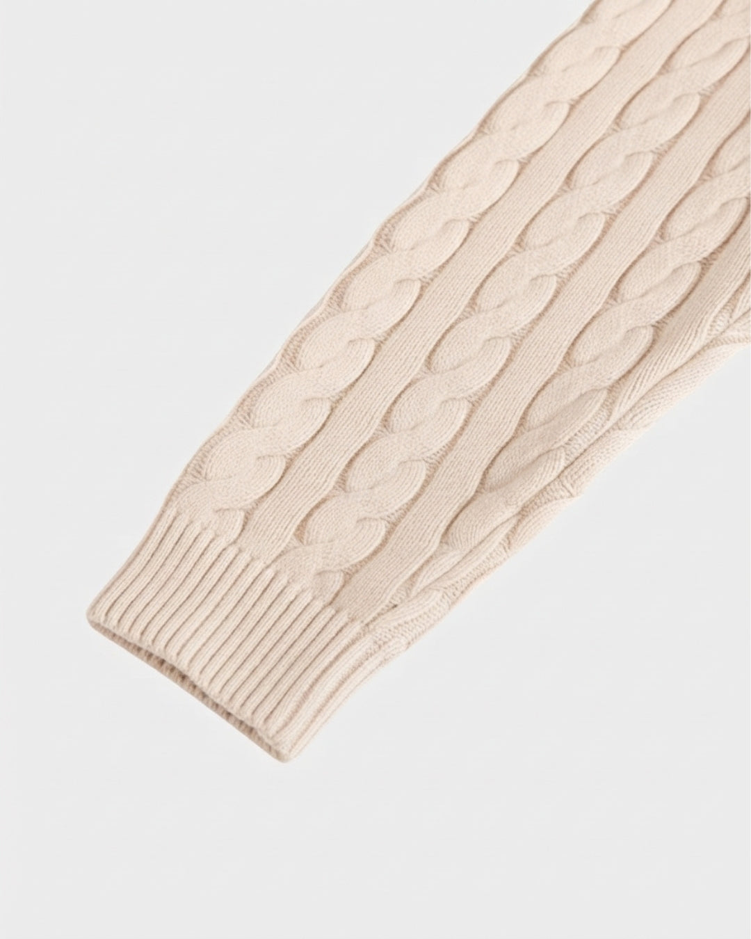 Cream-colored cotton cable knit sweater sleeve with a ribbed cuff.