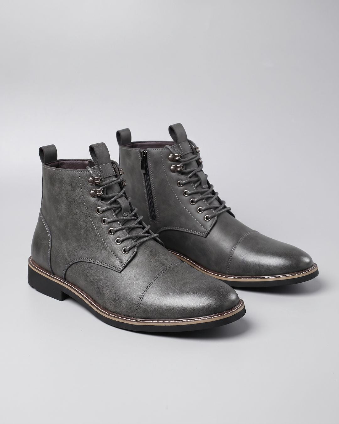 Grey men’s cap-toe ankle boots with lace-up front, metal eyelets, and convenient side zippers on a light background.