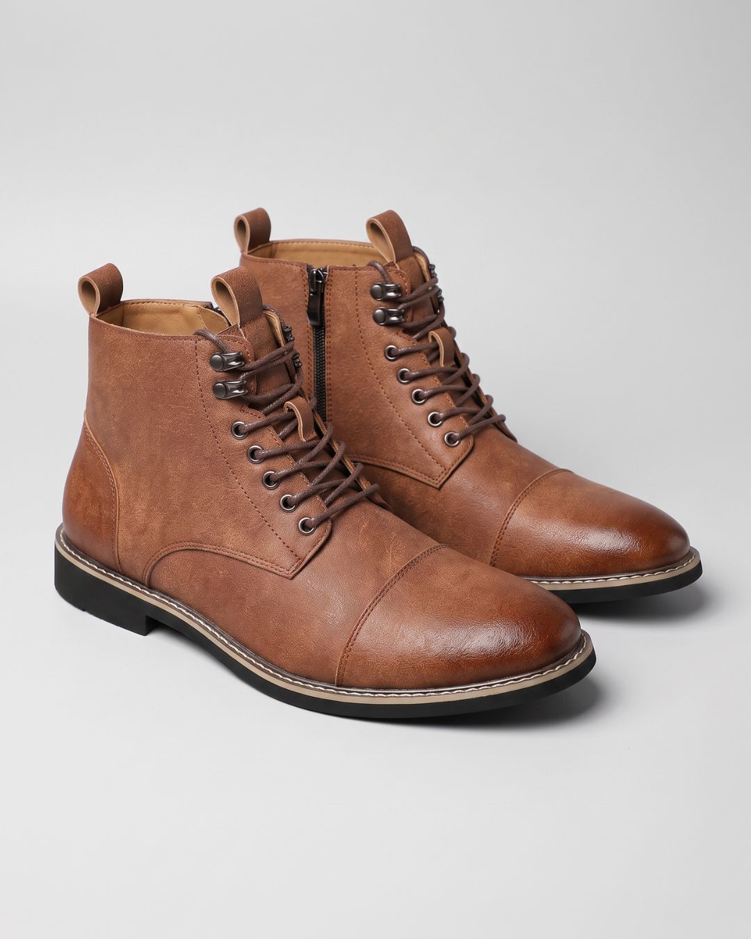 Brown leather cap-toe ankle boots with lace-up front, metal eyelets, and a convenient side zipper on a light background.