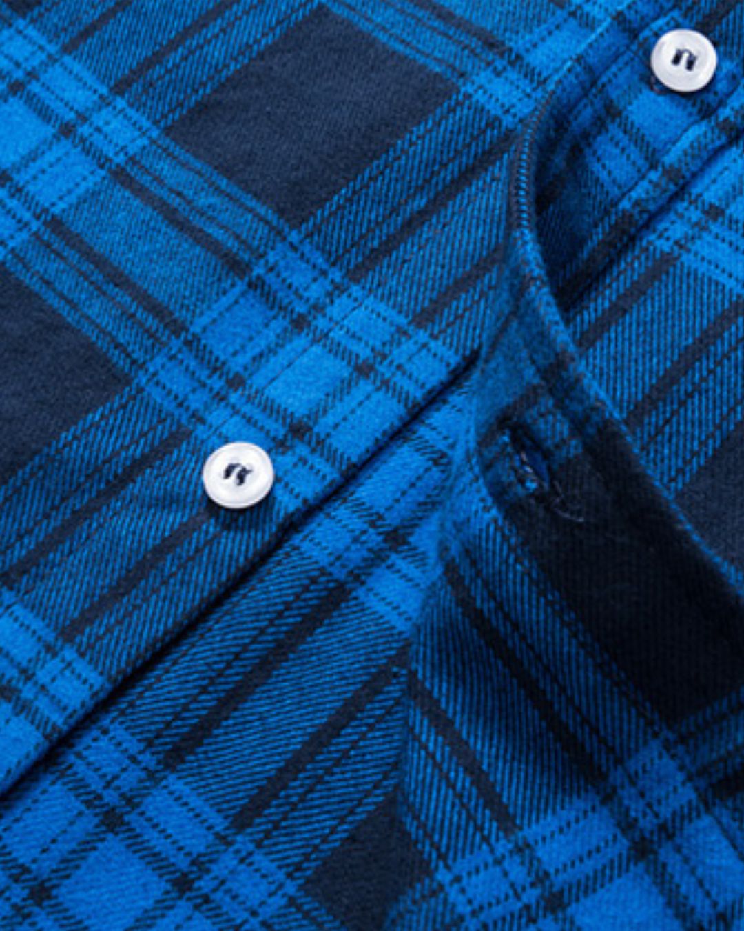 Close-up of a blue and black plaid flannel shirt featuring soft brushed fabric, a button-front placket, and white buttons.