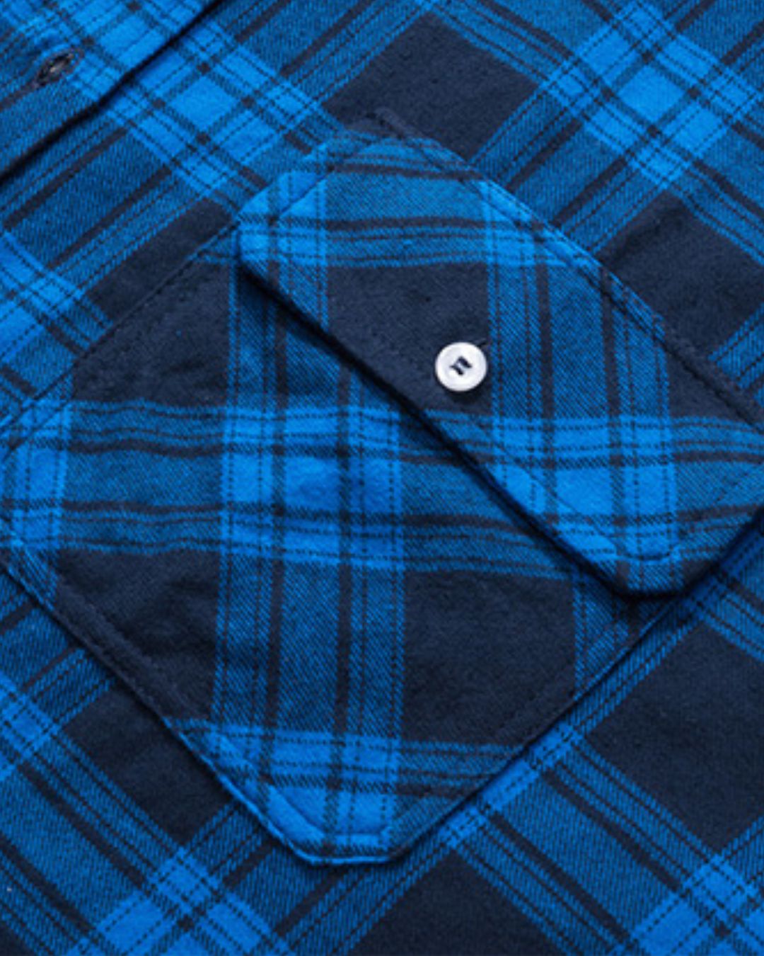 Close-up of a soft, brushed blue and black plaid flannel shirt featuring a buttoned chest pocket.