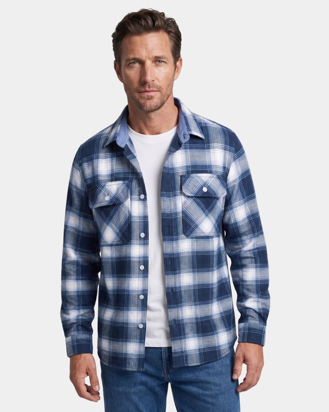 Man wearing a blue and white plaid flannel shirt with two chest pockets and a button-front design over a white t-shirt.