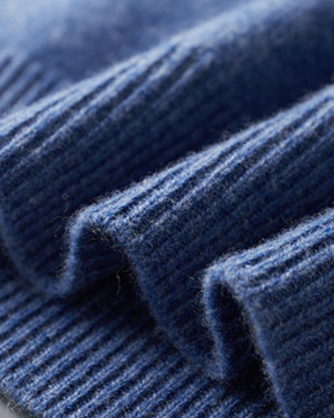 Close-up of a soft blue 100% wool sweater featuring a fine ribbed knit texture and high-quality construction.