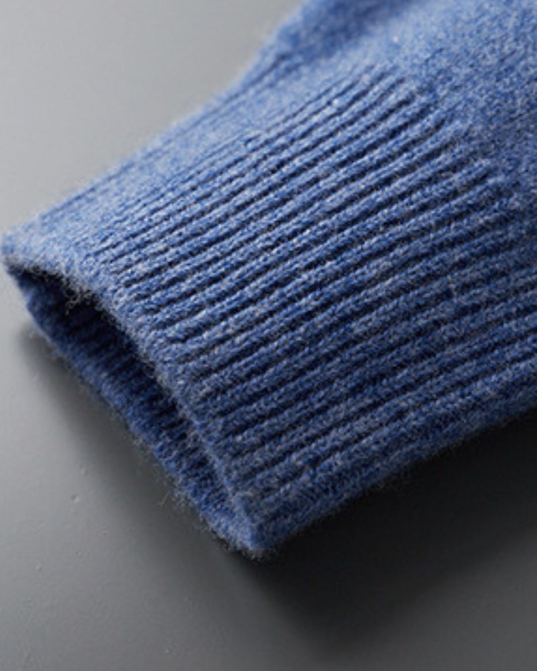 Close-up of a blue wool sweater sleeve featuring a soft knit texture and a ribbed cuff.