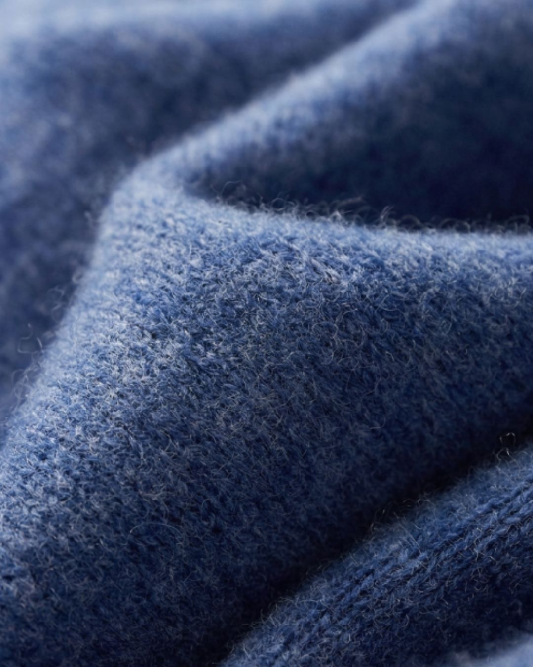 Close-up of a soft, blue 100% wool knit fabric with a textured, cozy finish.
