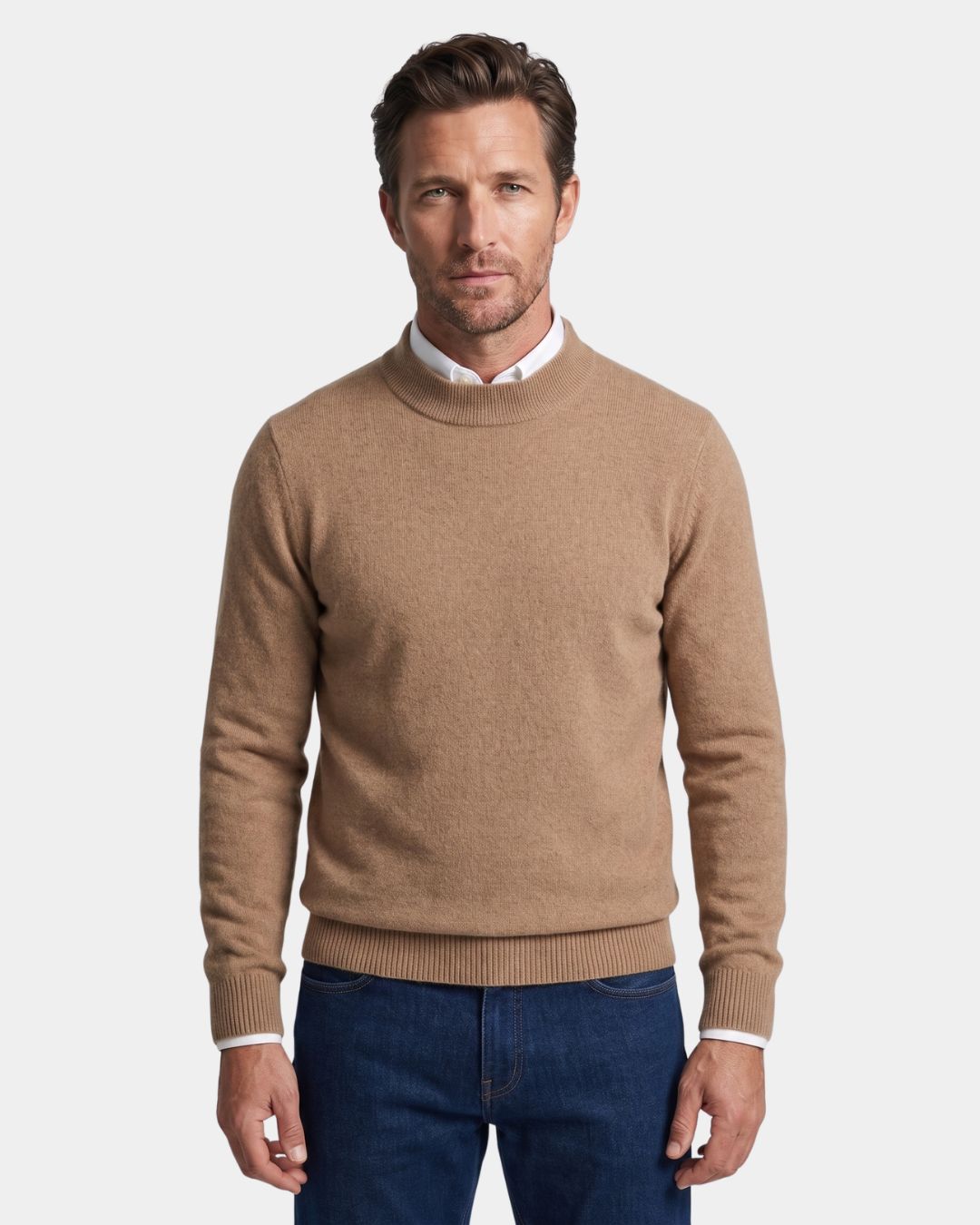 Man wearing a tan 100% wool mock neck sweater with ribbed cuffs over a white collared shirt and blue jeans.