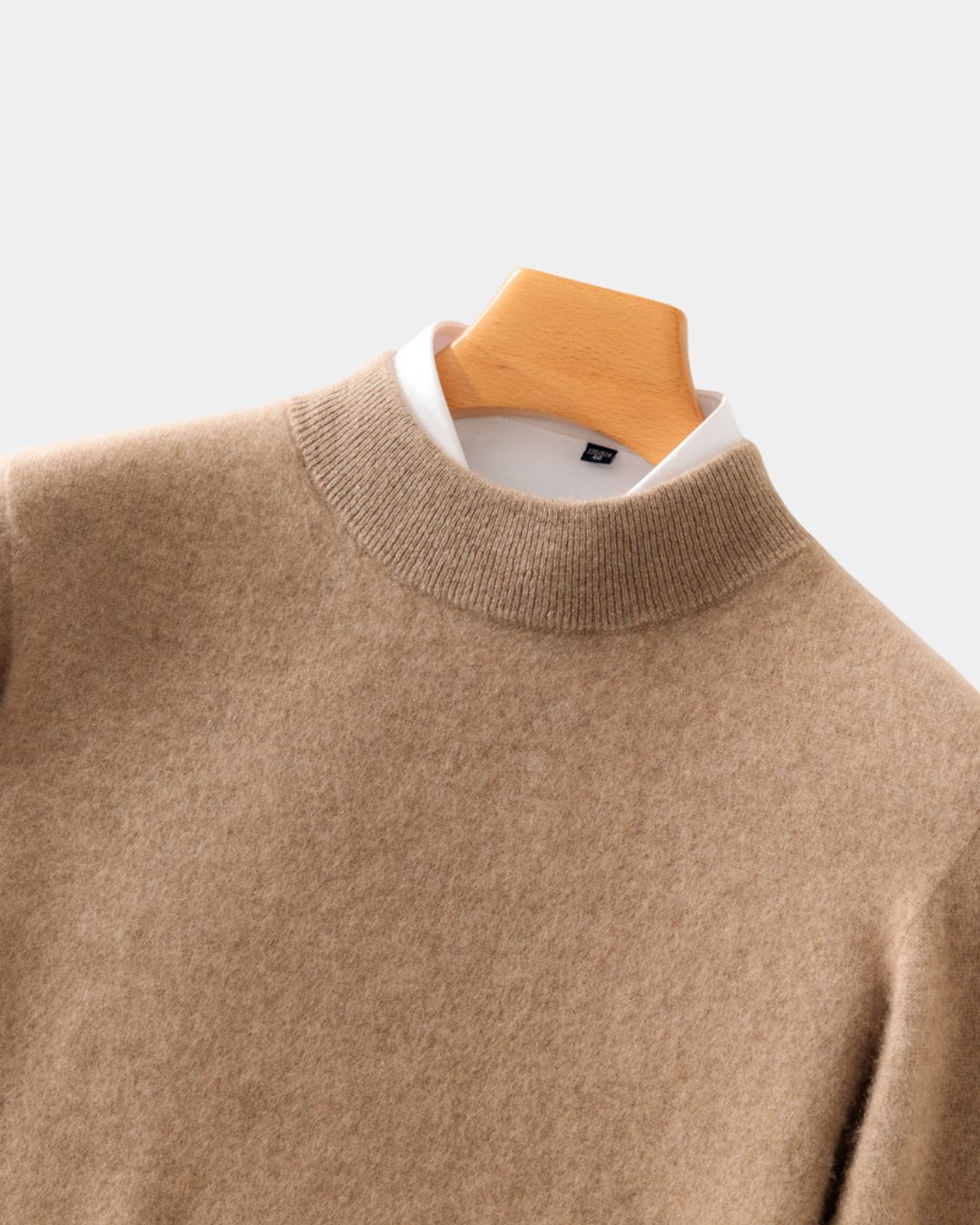 Tan men's mock neck sweater in soft pure wool, layered over a white collared shirt on a wooden hanger.