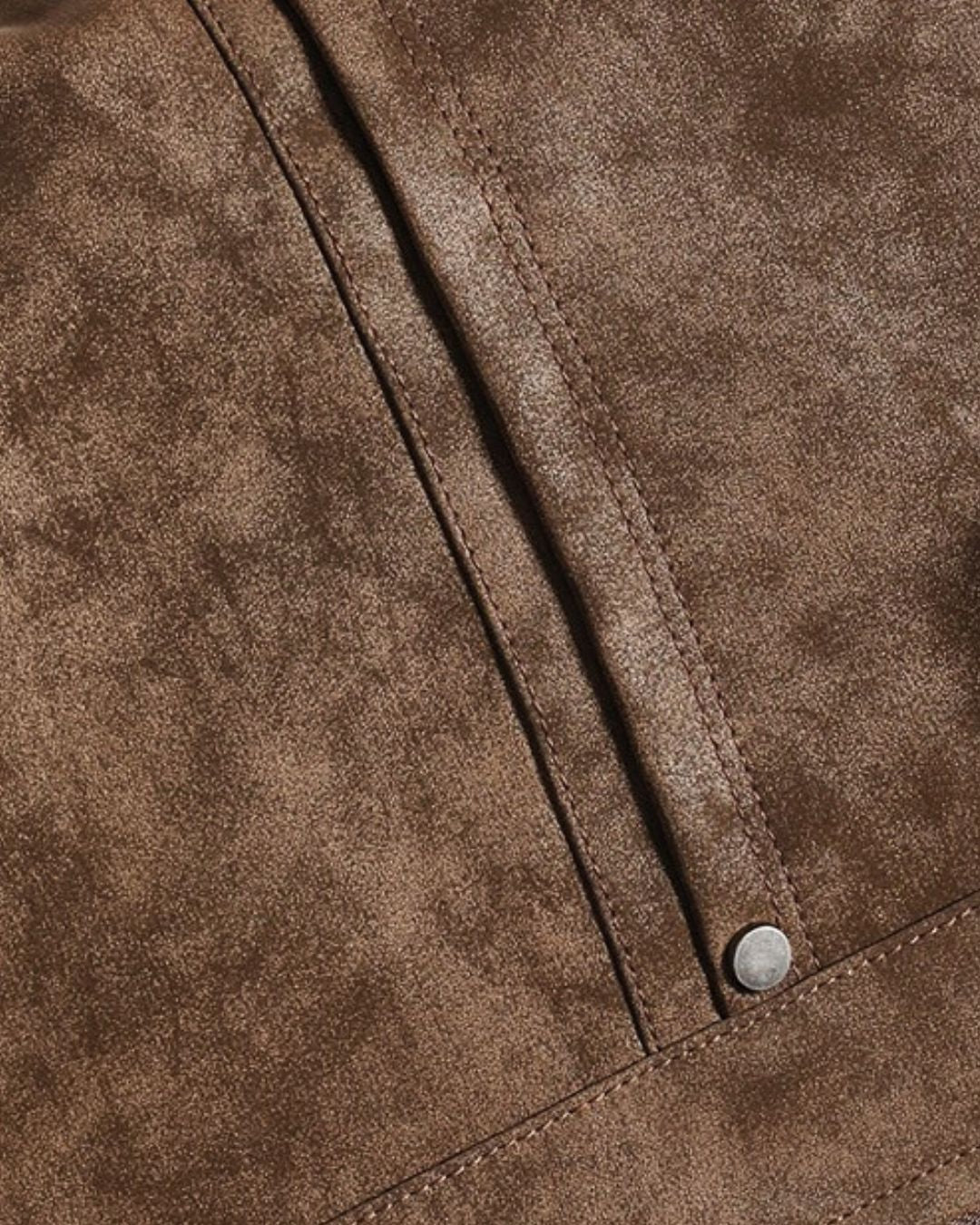 Close-up of a brown bomber jacket with a single silver snap button on a stitched tab.