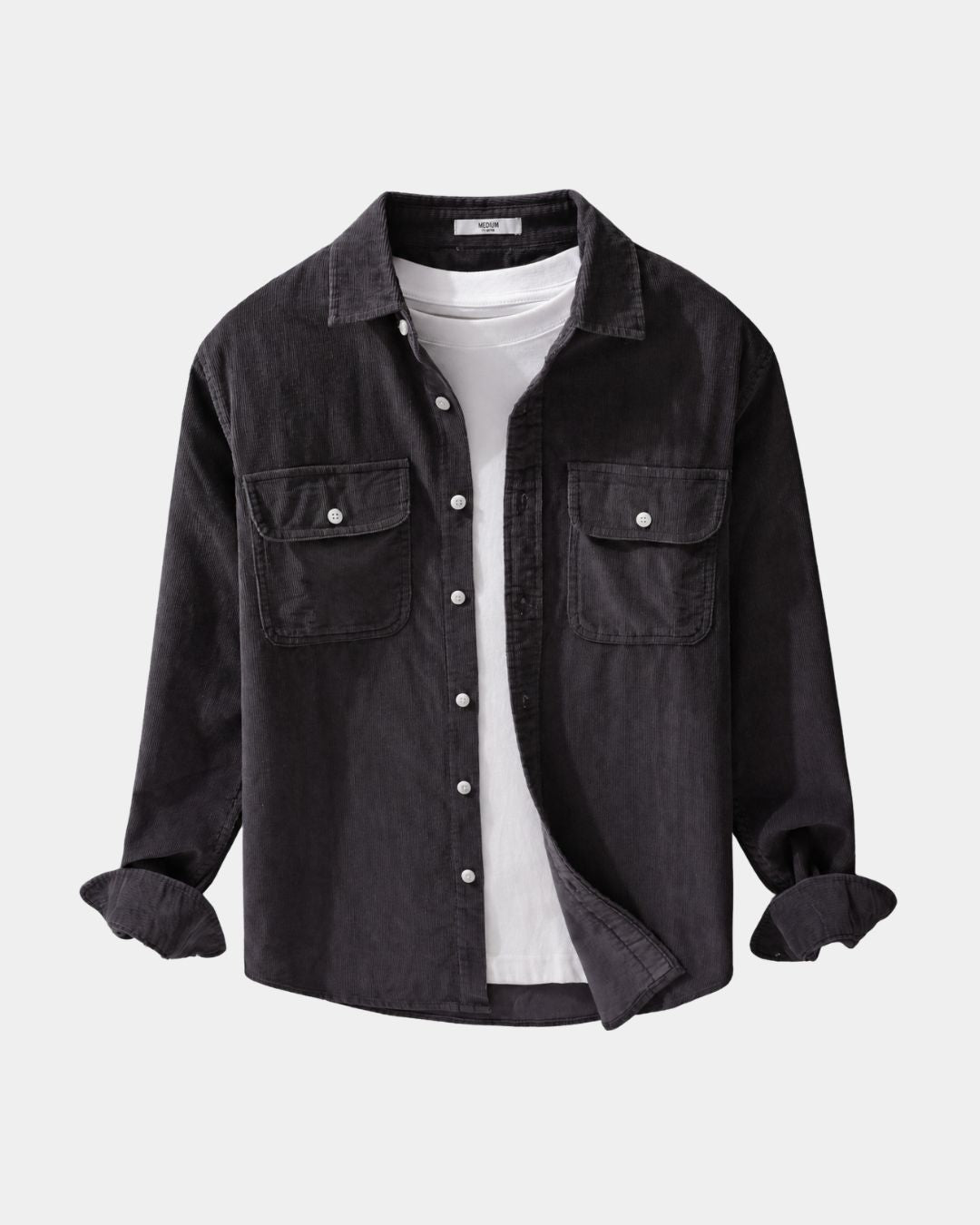 Dark charcoal cotton corduroy button-up shirt with chest pockets and dropped shoulders worn over a white T-shirt.